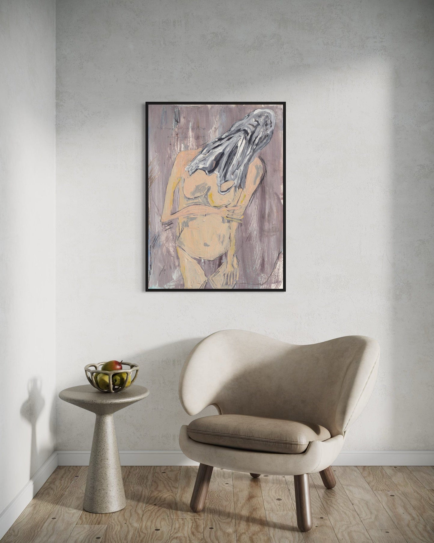 Framed abstract art of a nude figure on a wall above a beige chair and small table.