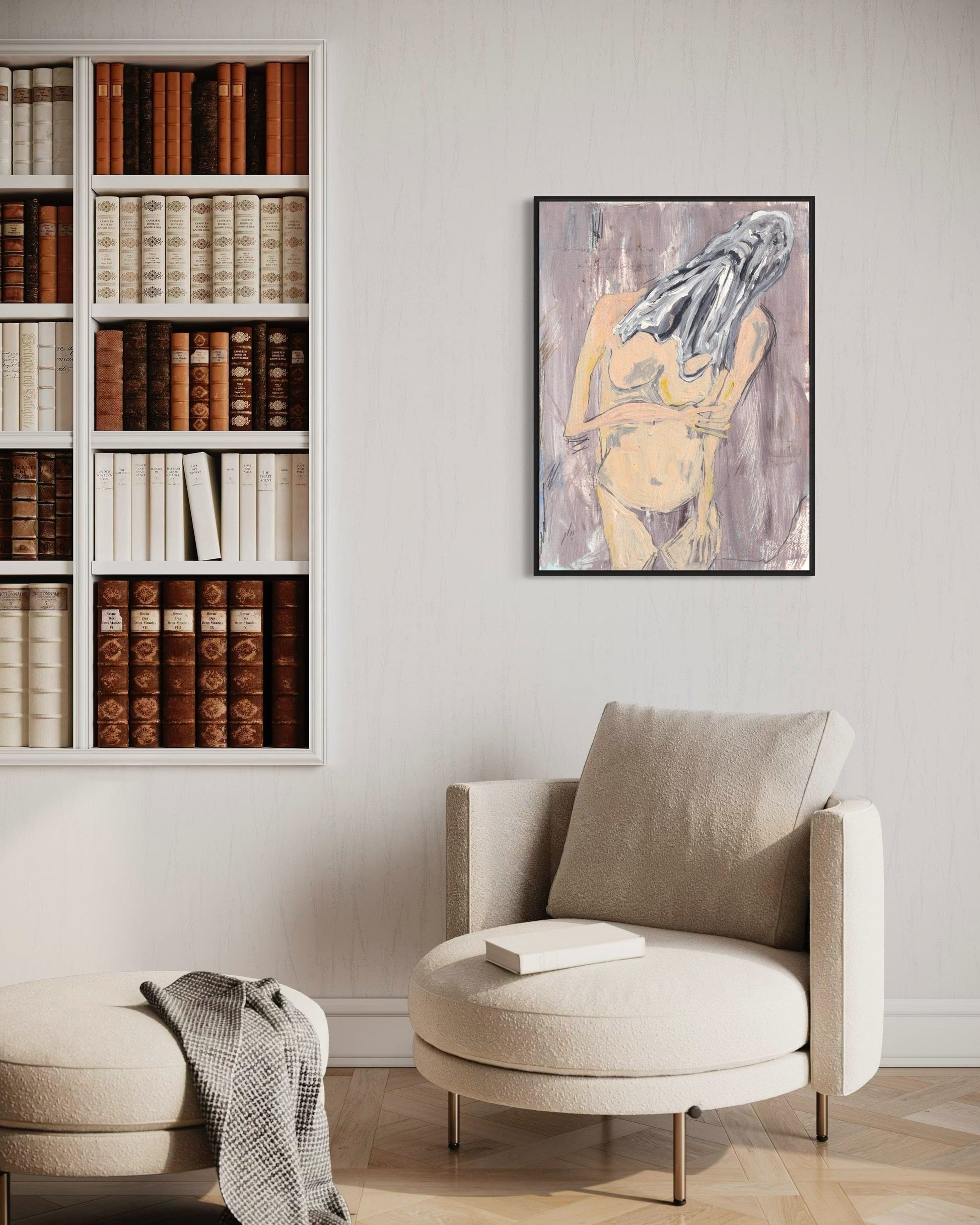 Beige armchair with a bookshelf and framed artwork in a room.