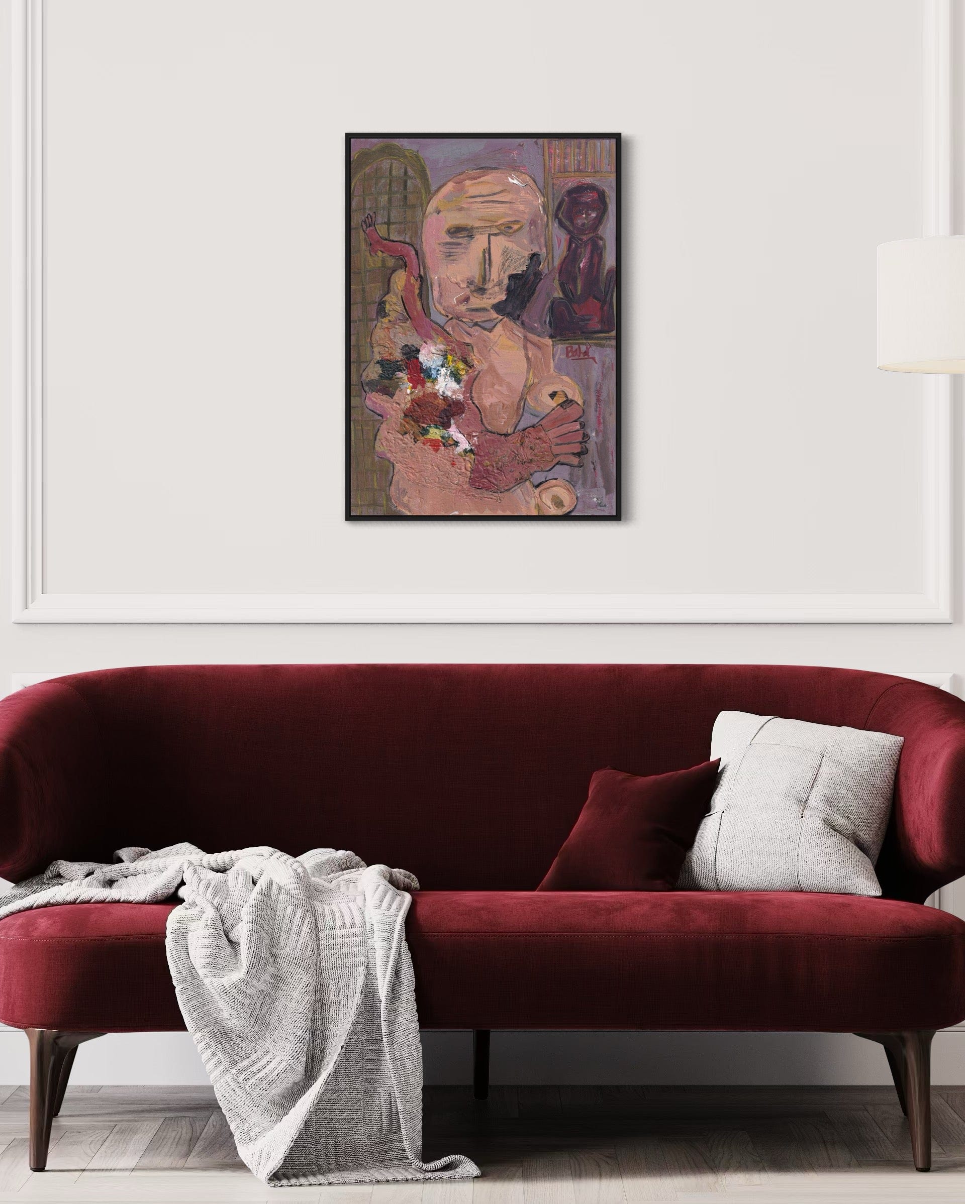 Red sofa with a white blanket and gray pillow, framed artwork above on a white wall.