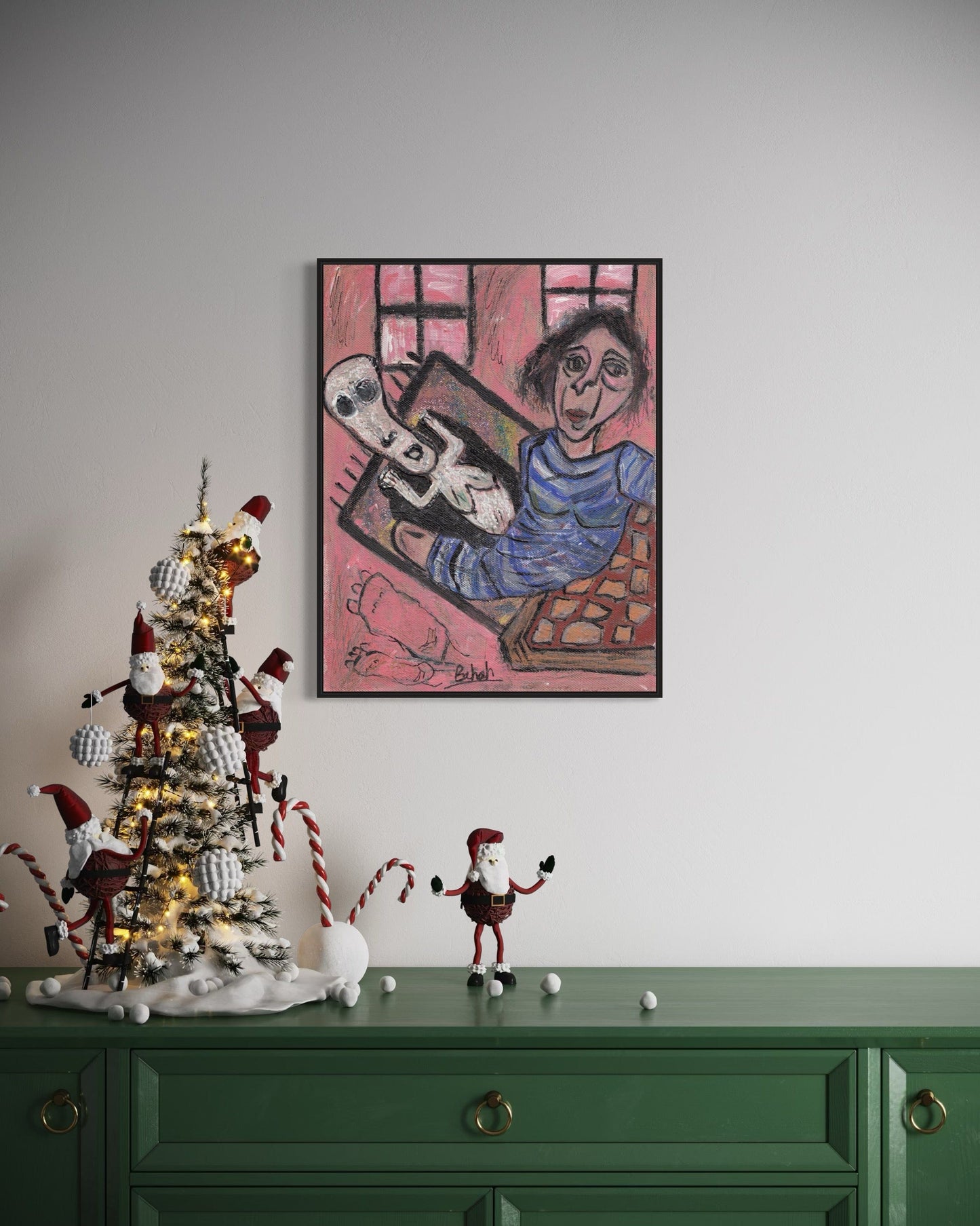 Decorative Christmas tree with ornaments on a green cabinet, framed artwork on the wall.