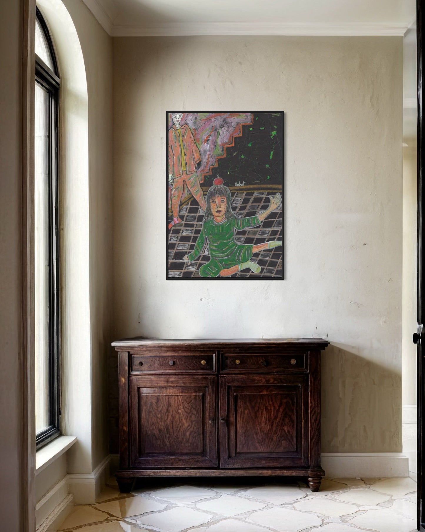 Framed artwork on a wall above a wooden cabinet in a room with a window.