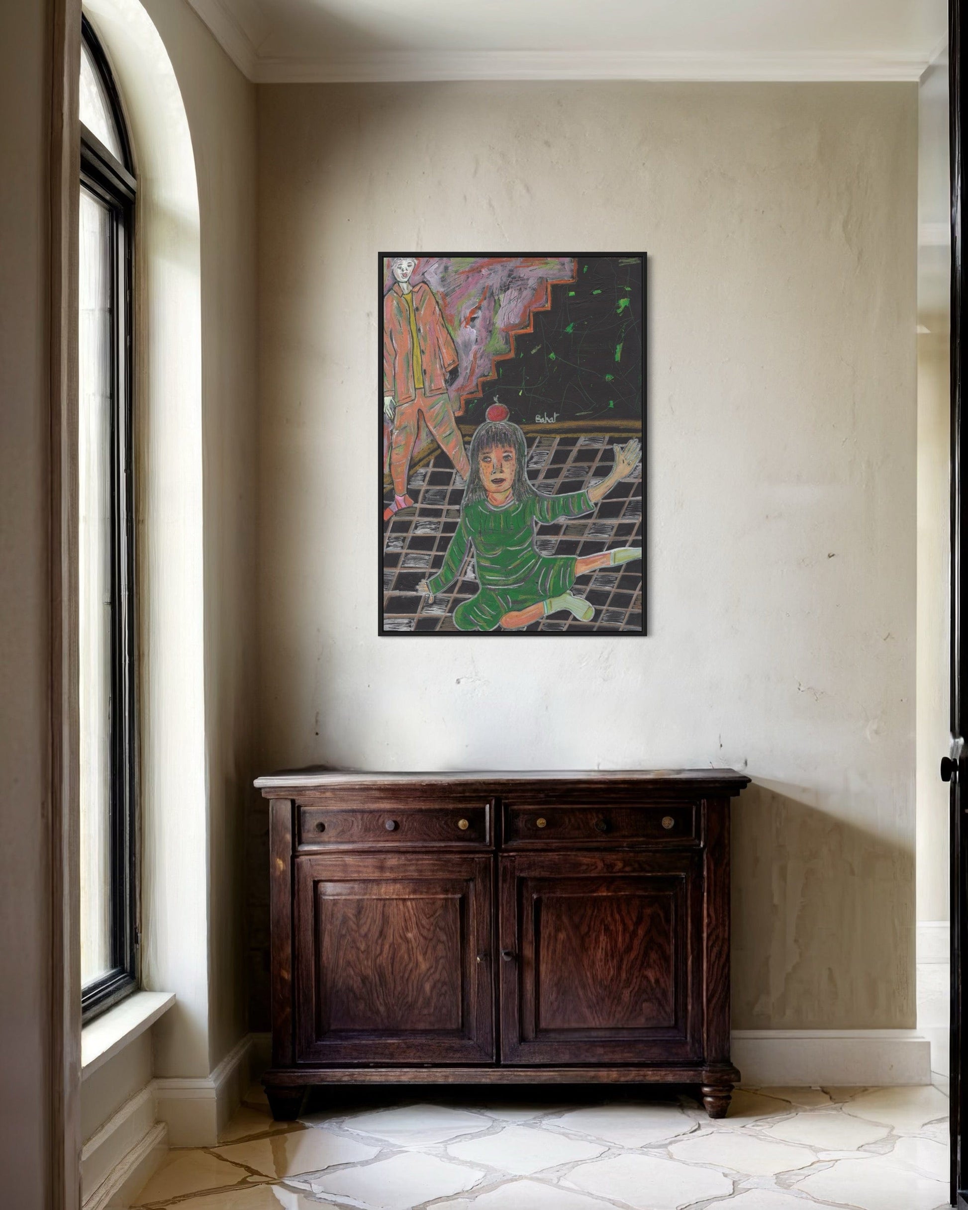 Framed artwork on a wall above a wooden cabinet in a room with a window.