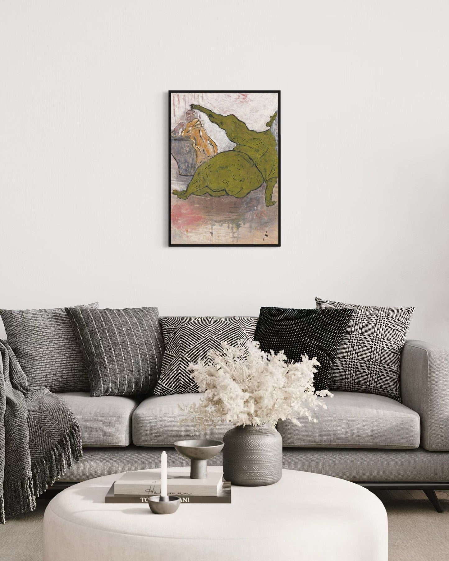 Living room with a gray sofa, decorative pillows, a coffee table with a vase and candles, and a framed abstract art piece on the wall.