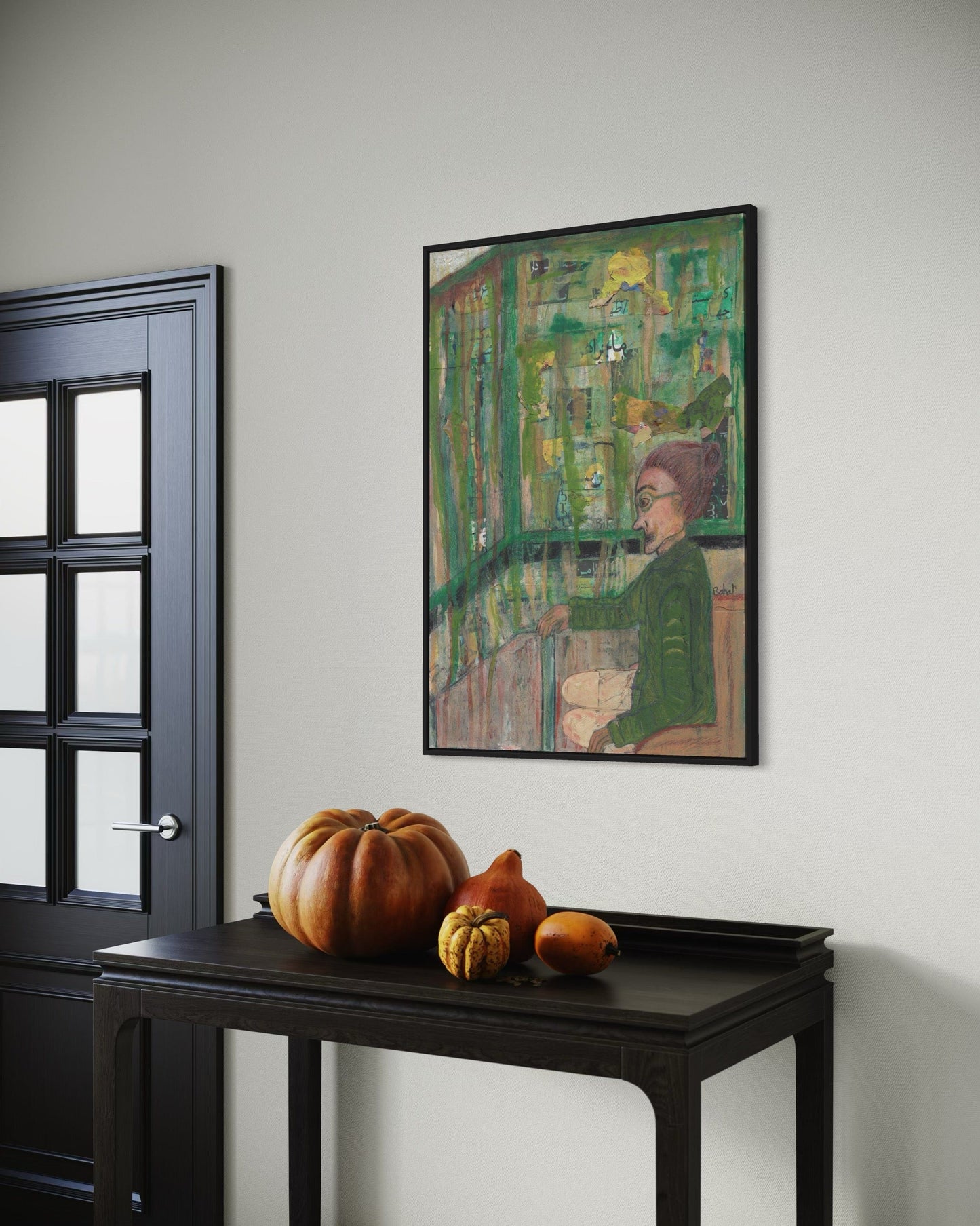 Framed artwork on a wall with pumpkins on a table below.