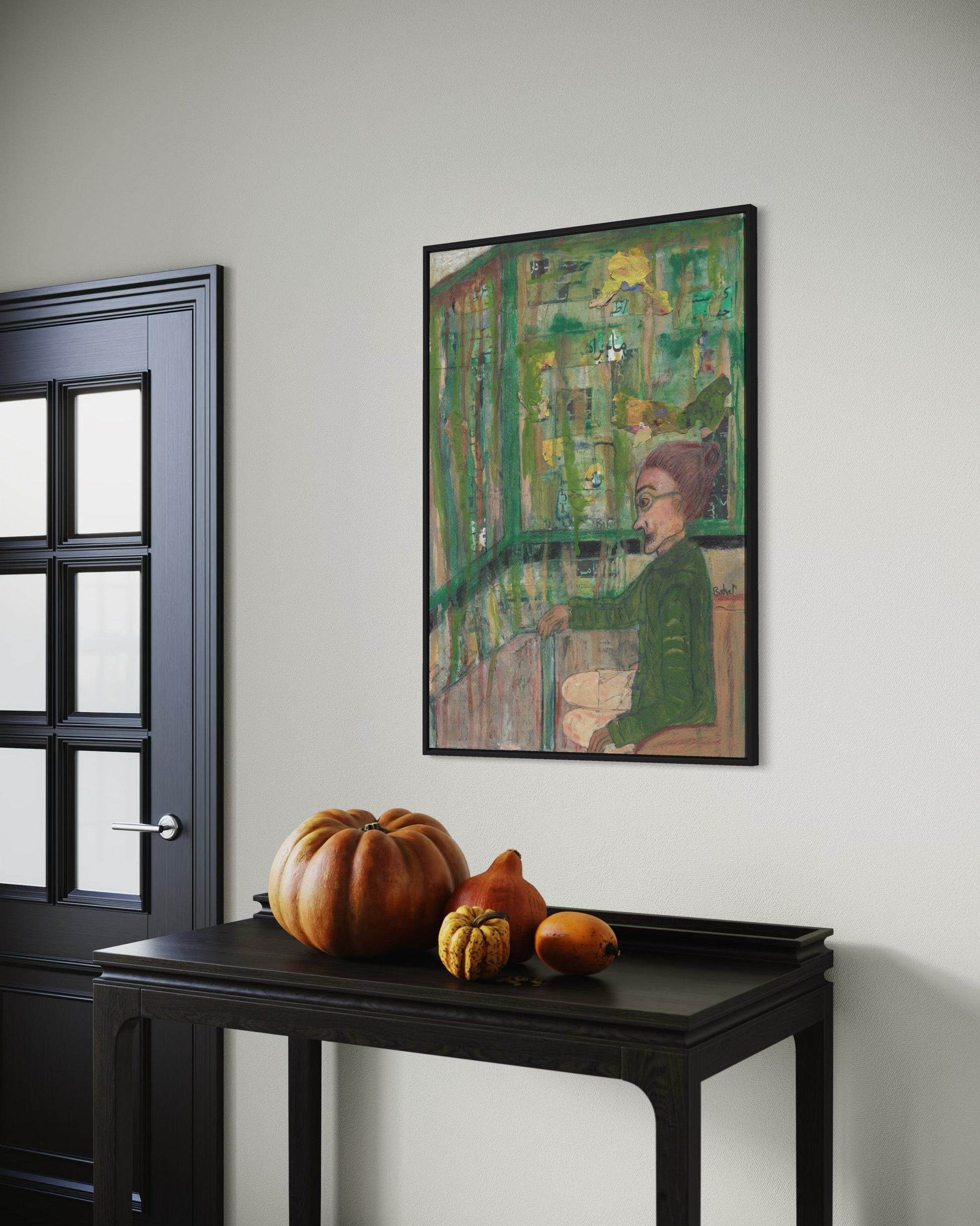 Framed artwork on a wall with pumpkins on a table below.