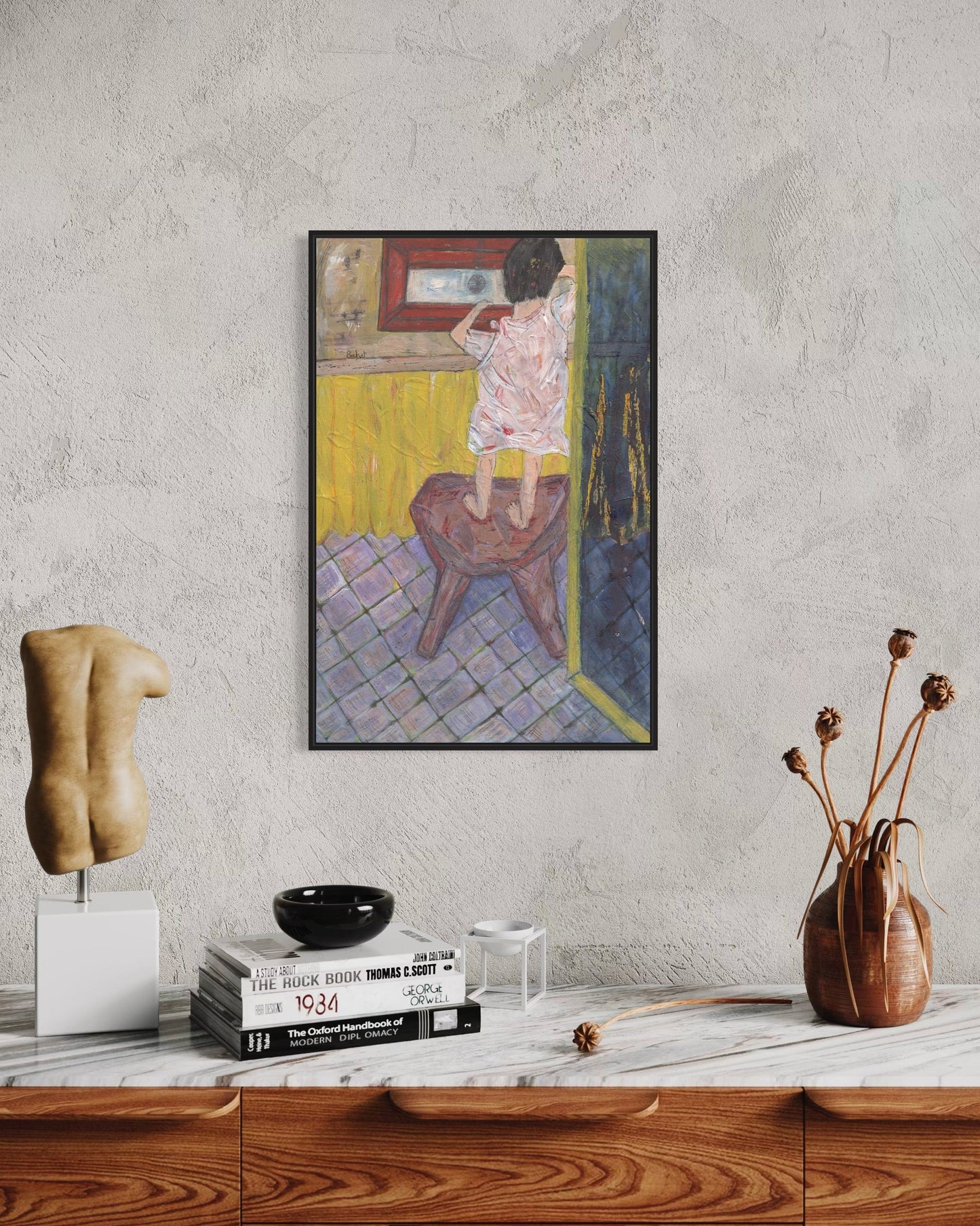 Framed artwork on a wall above a wooden cabinet with decorative items.