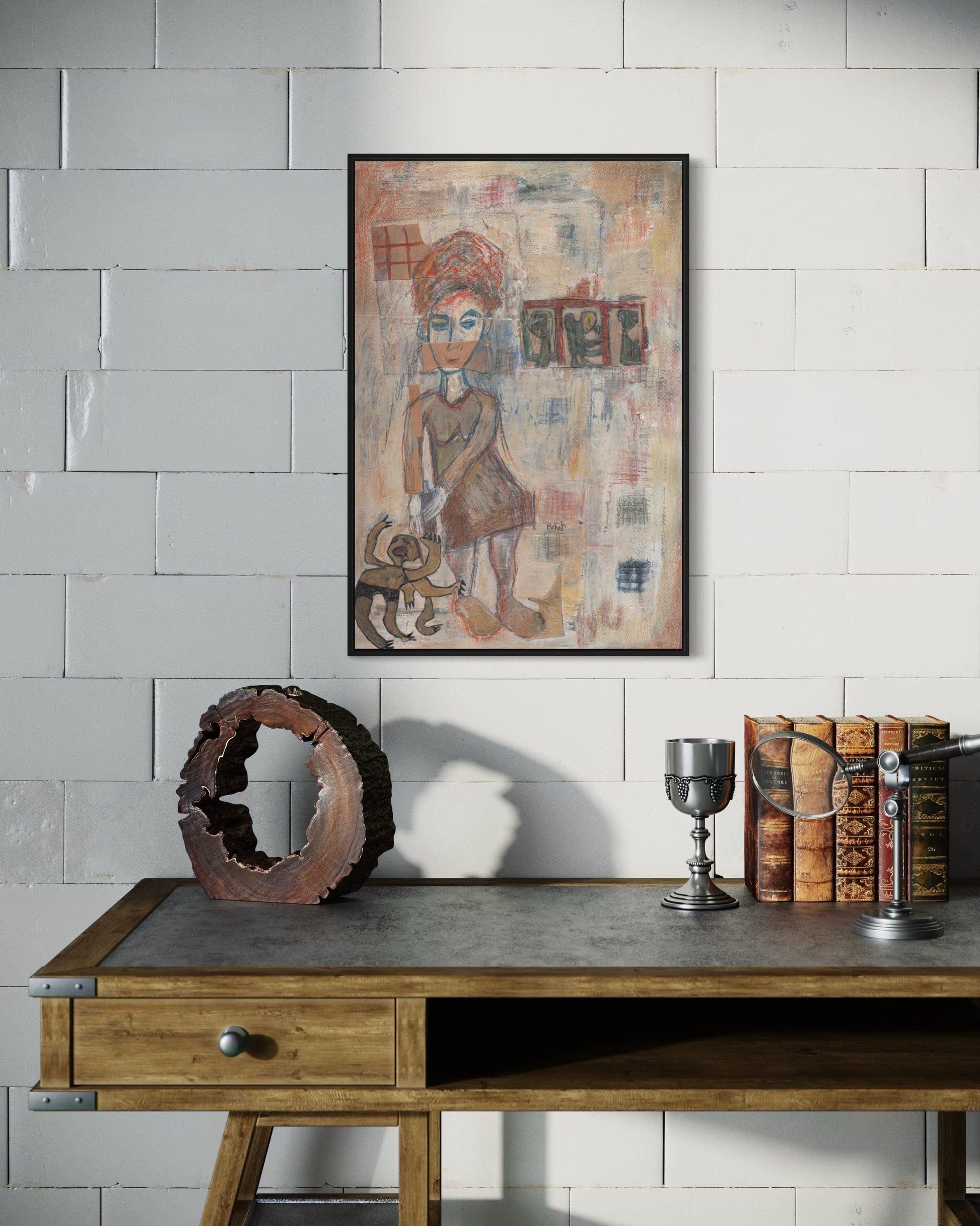 Framed artwork on a wall above a wooden desk with decorative items.