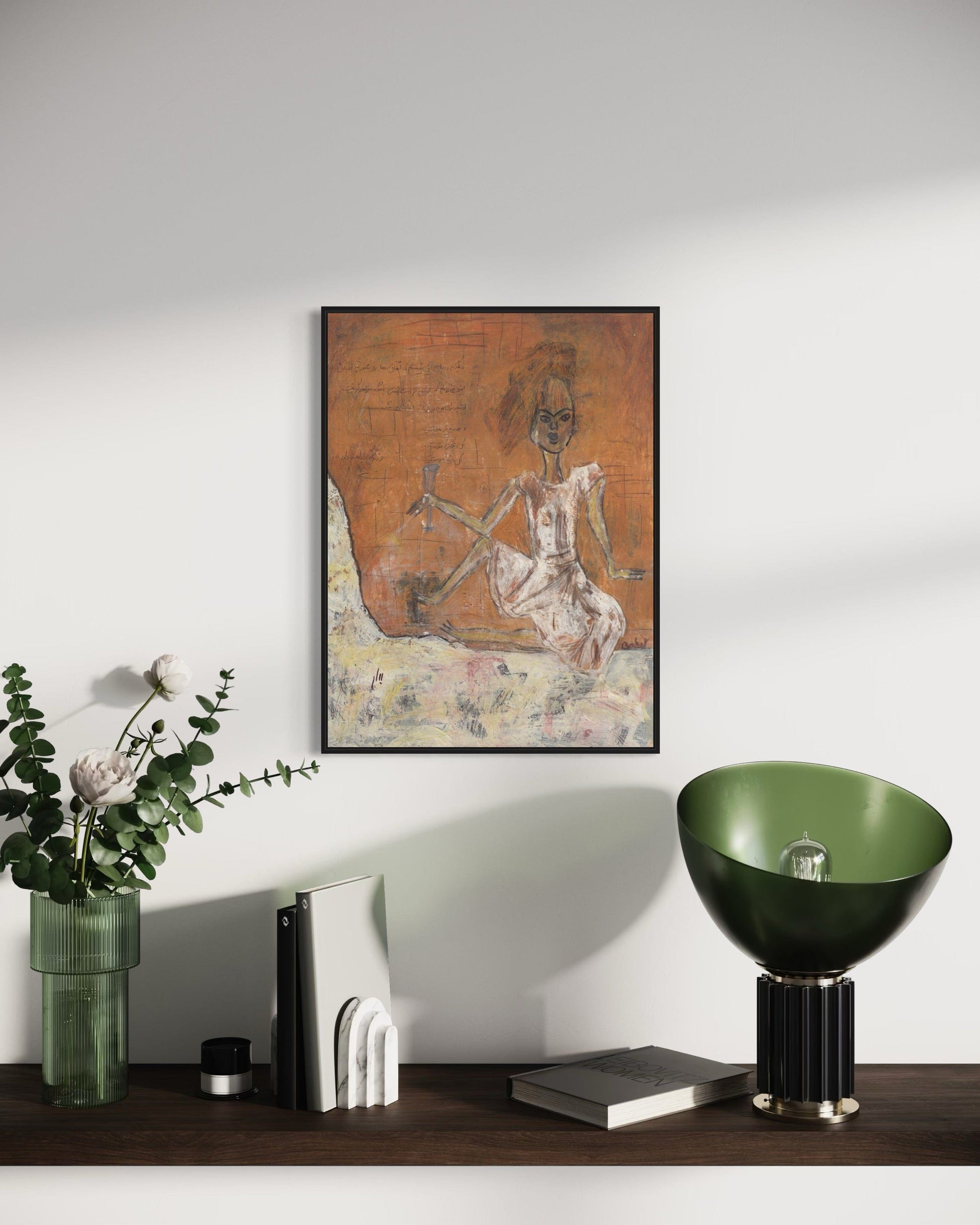 Framed artwork on a wall with decorative items on a shelf below.