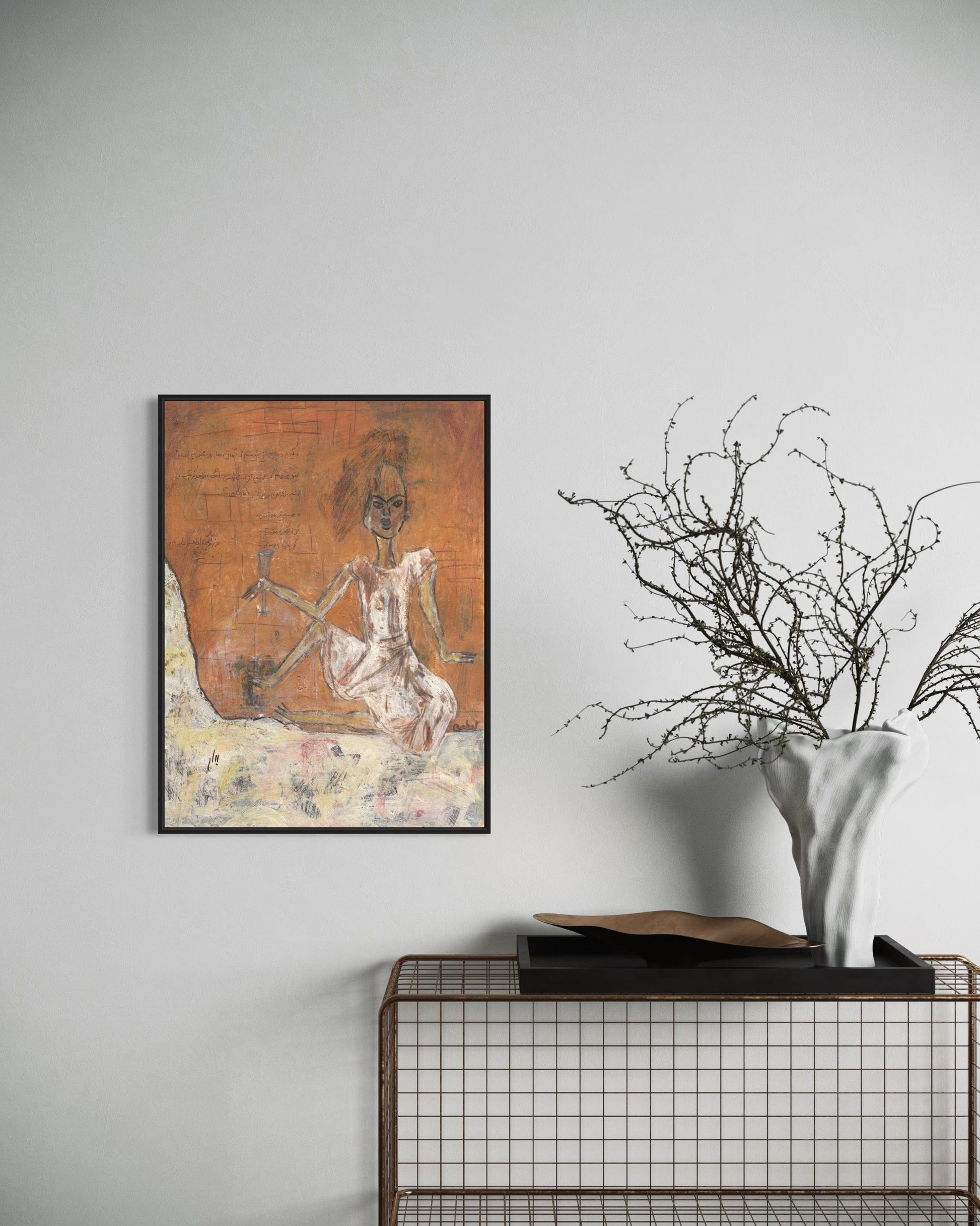 Framed artwork on a wall with a vase and branches below.