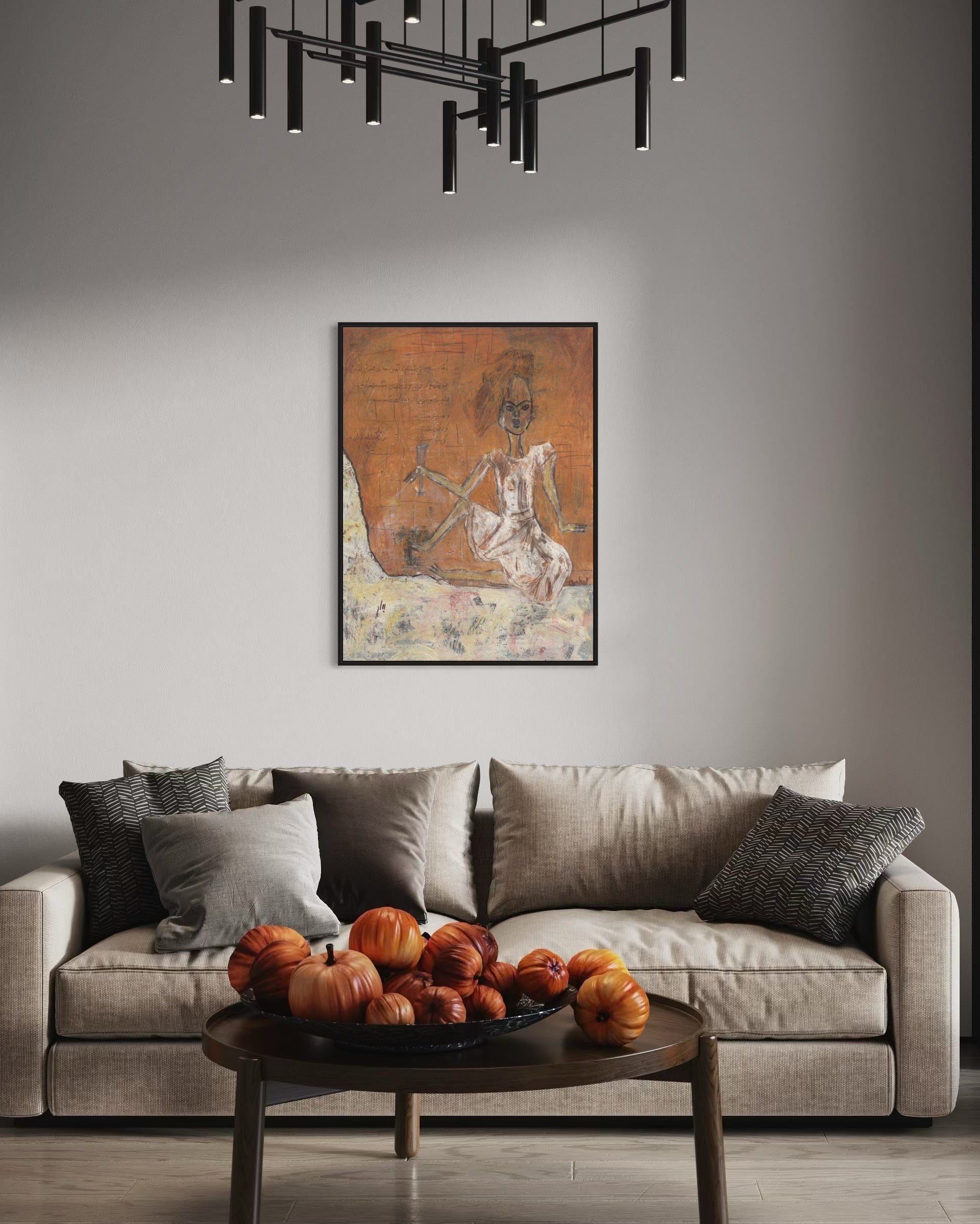 Living room with a beige sofa, decorative pillows, a coffee table with pumpkins, and a framed artwork on the wall.