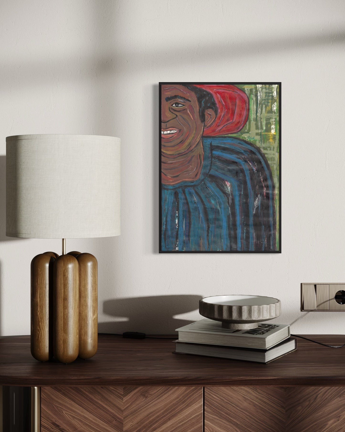 Framed artwork of a person on a wall above a wooden desk with decorative items.