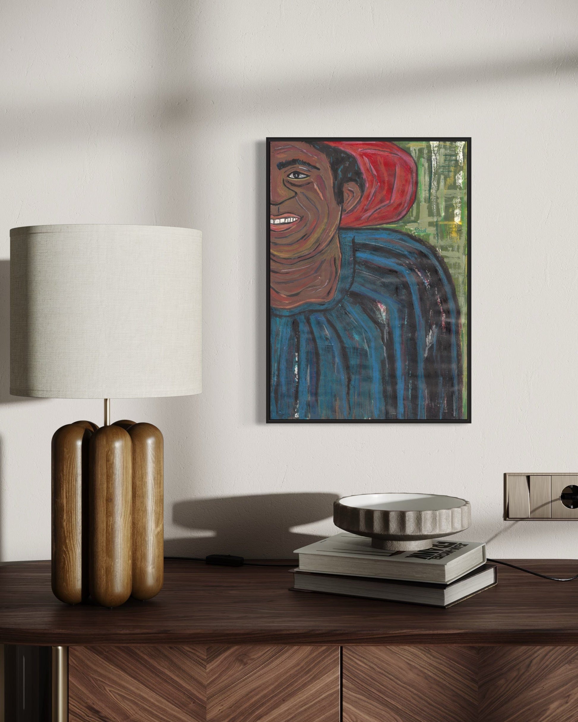 Framed artwork of a person on a wall above a wooden desk with decorative items.