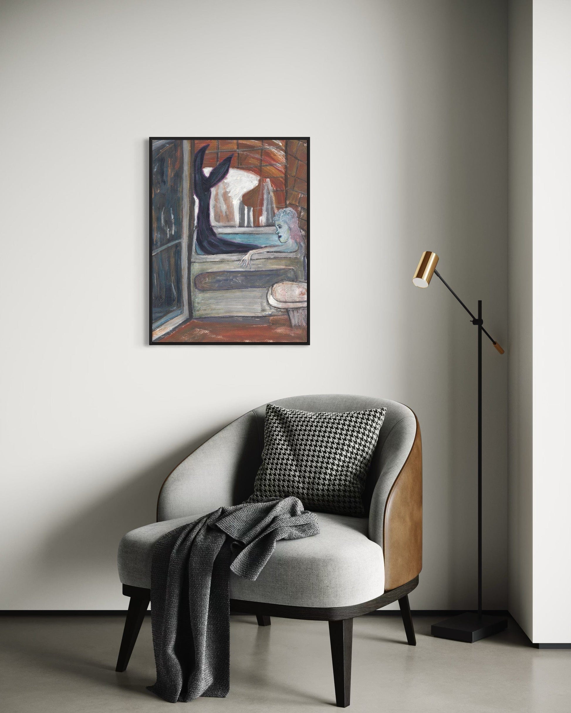 Modern interior with a gray armchair, plaid pillow, and framed artwork on a white wall.