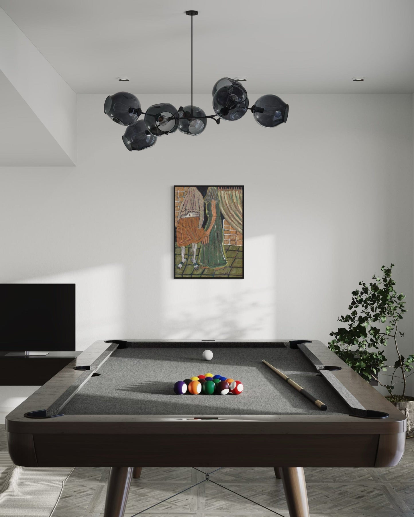 Modern pool table with colorful balls in a room with a chandelier and framed artwork.