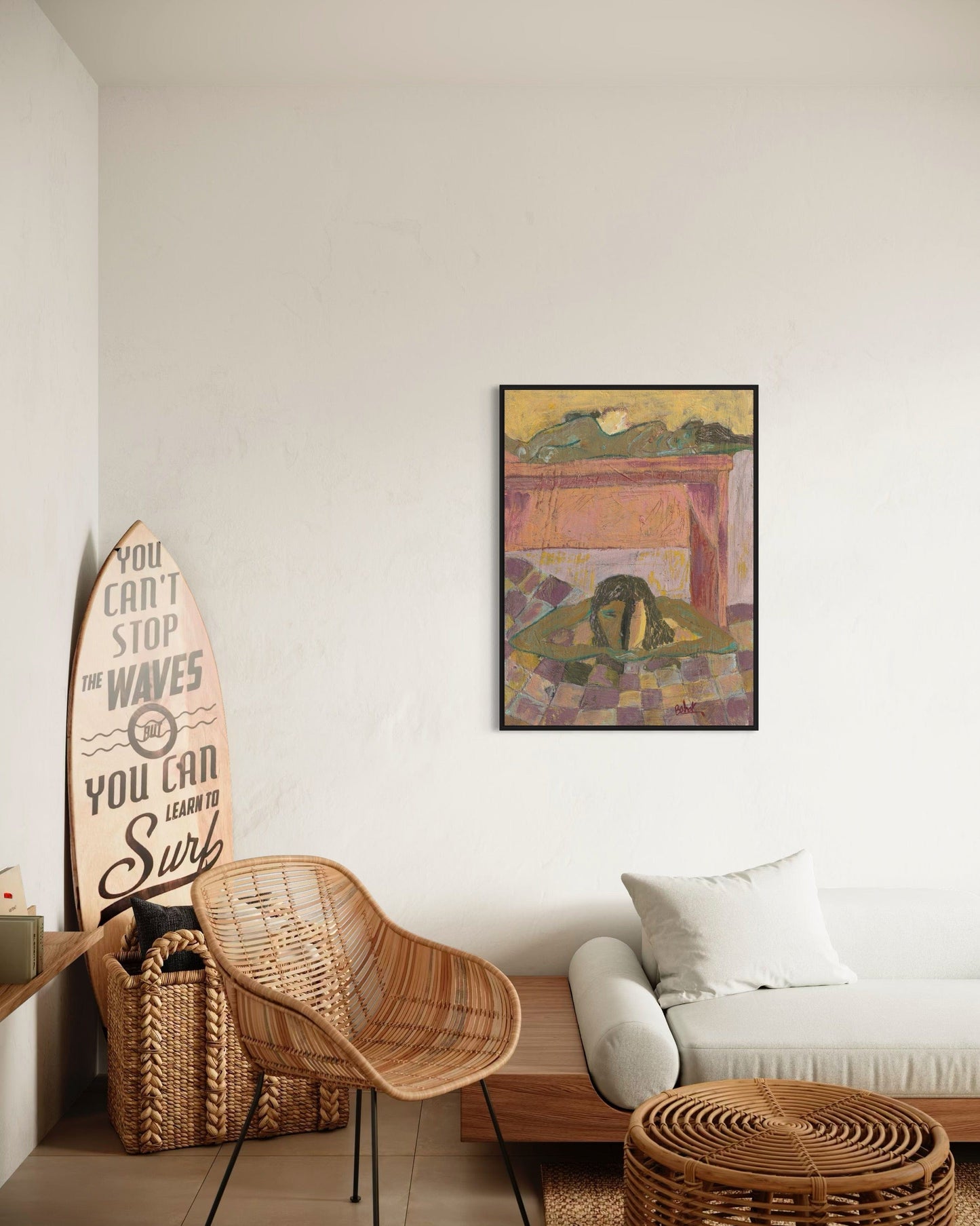 Living room with wicker chair, surfboard, and framed artwork on a white wall.