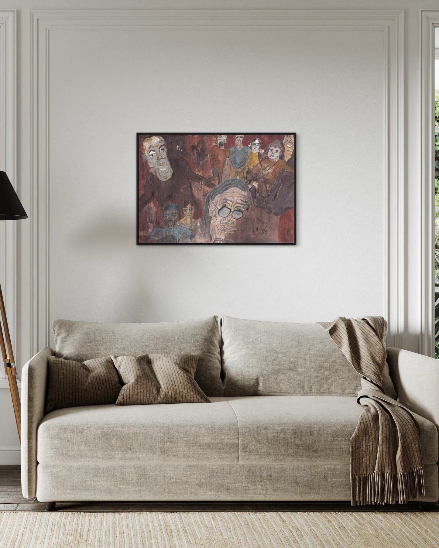 Beige sofa with decorative pillows and a blanket in a room with a painting on the wall.