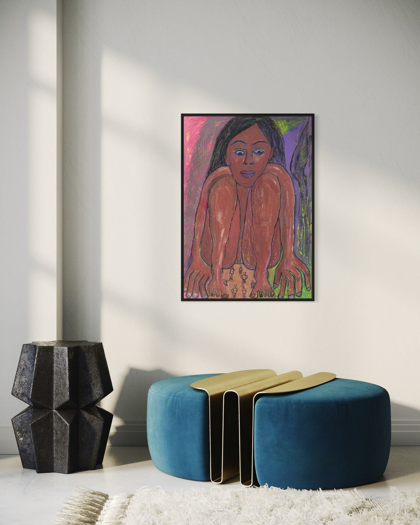Framed artwork of a woman's portrait on a wall with a blue ottoman and black vase below.