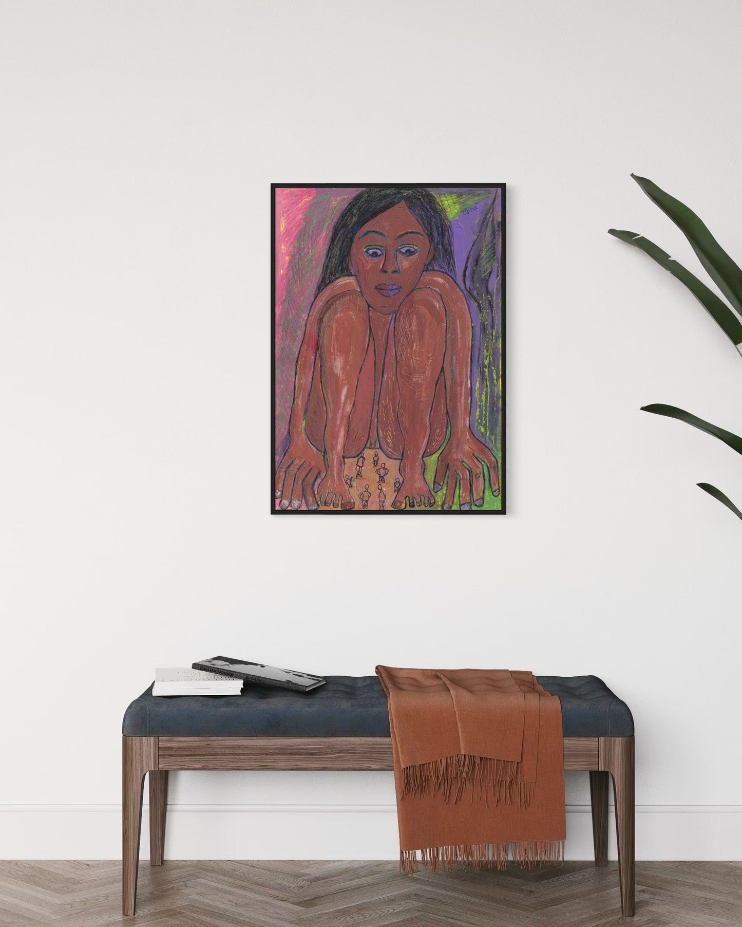 Framed artwork of a person on a wall above a bench with a brown blanket.