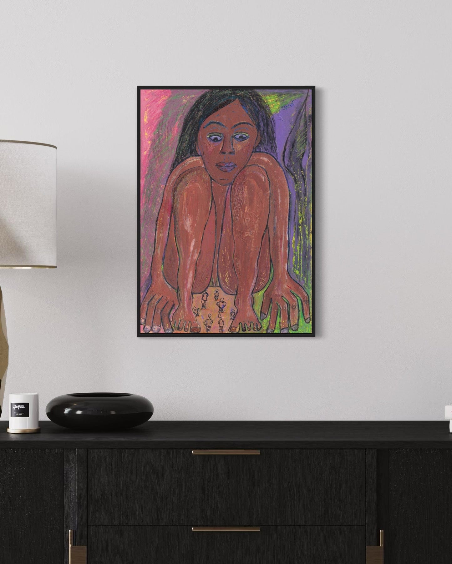 Framed artwork of a stylized figure on a white wall above a black cabinet.