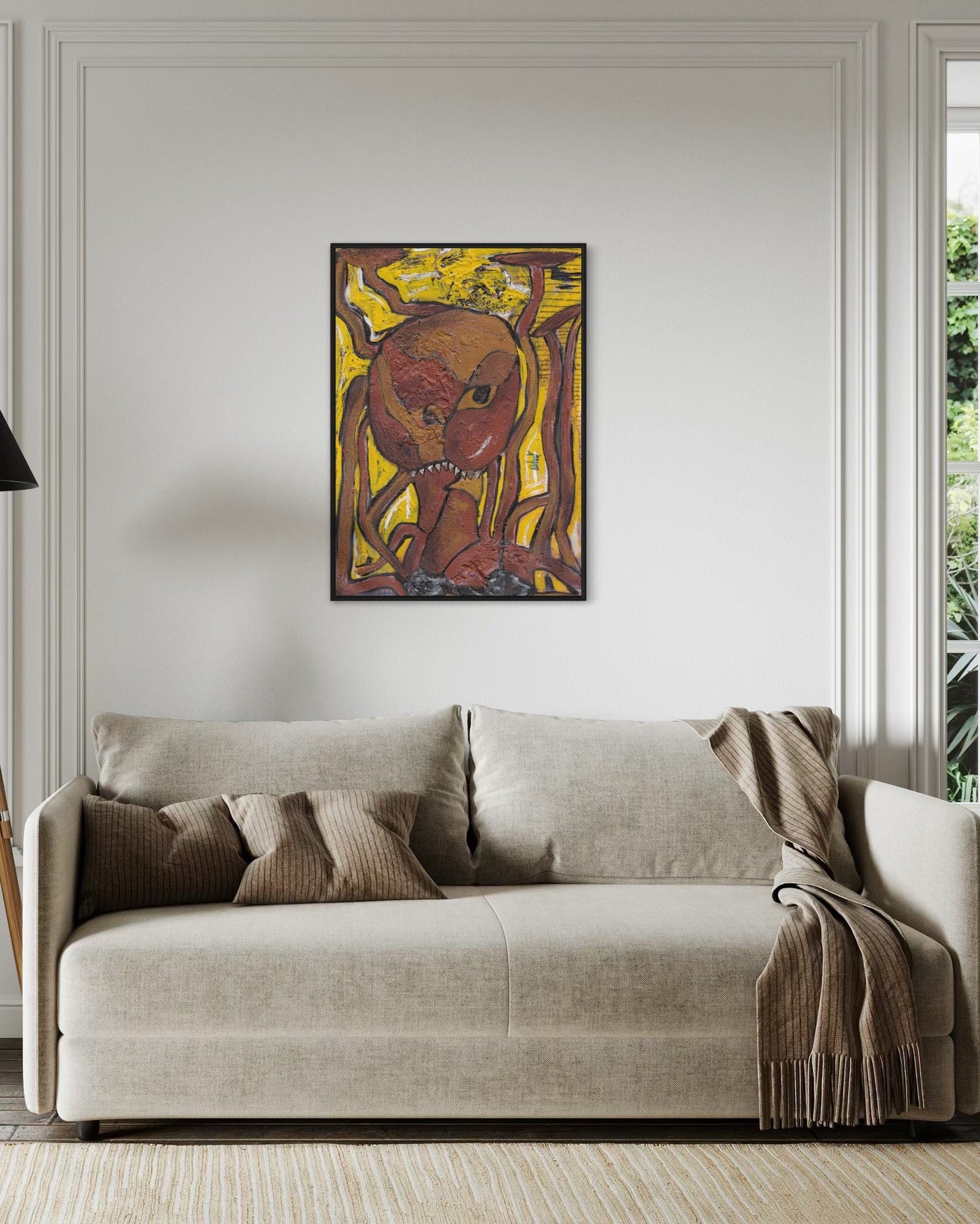 Beige sofa with decorative pillows and a blanket in a room with a wall painting.