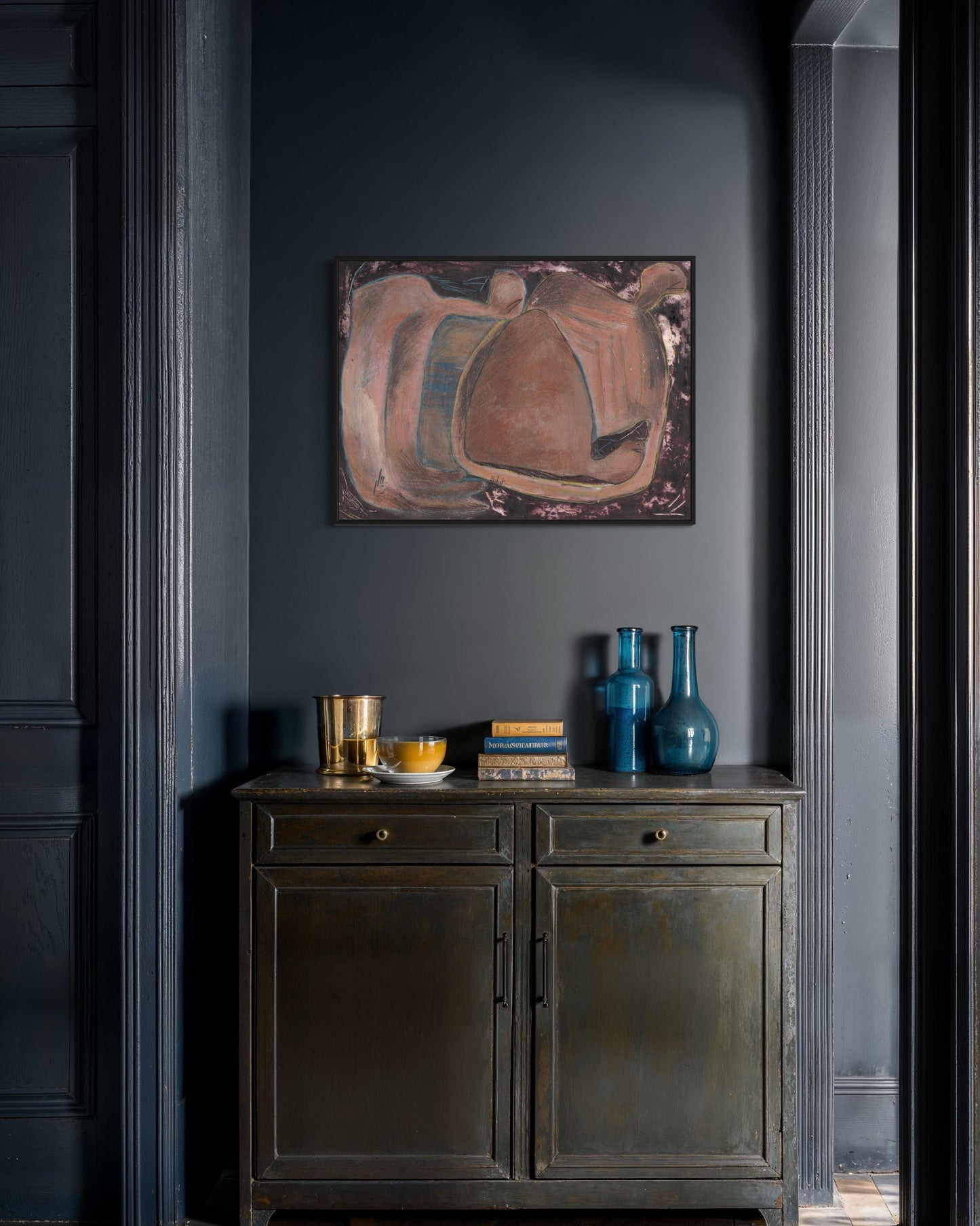 Dark gray wall with abstract painting and decorative items on a wooden cabinet