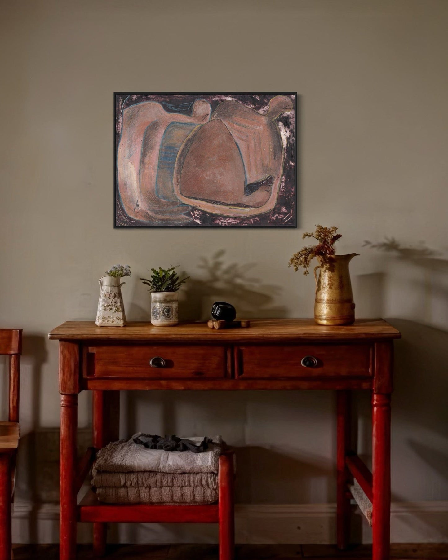 Wooden table with decorative items against a wall with abstract art