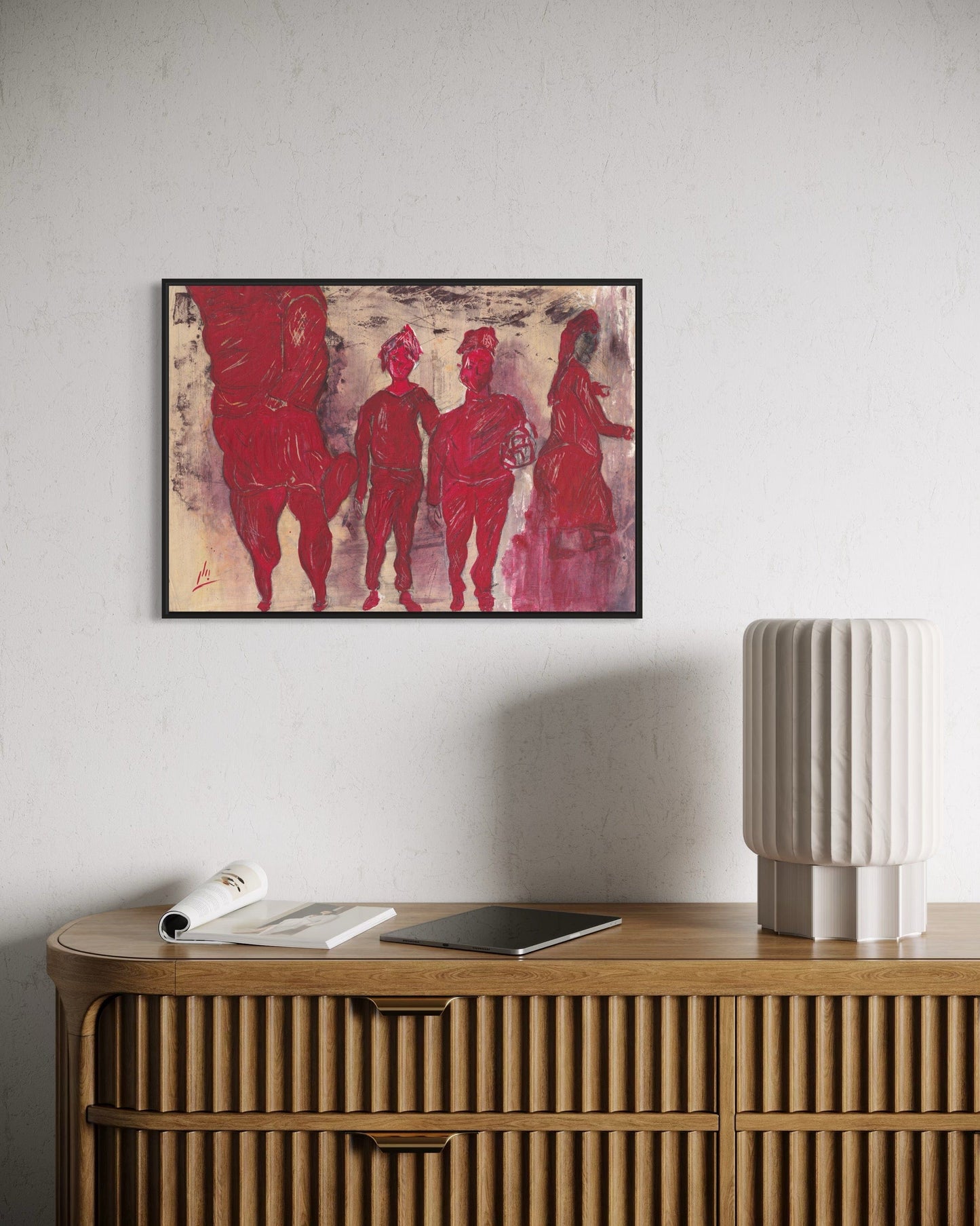 Framed artwork of red figures on a white wall above a wooden console table.