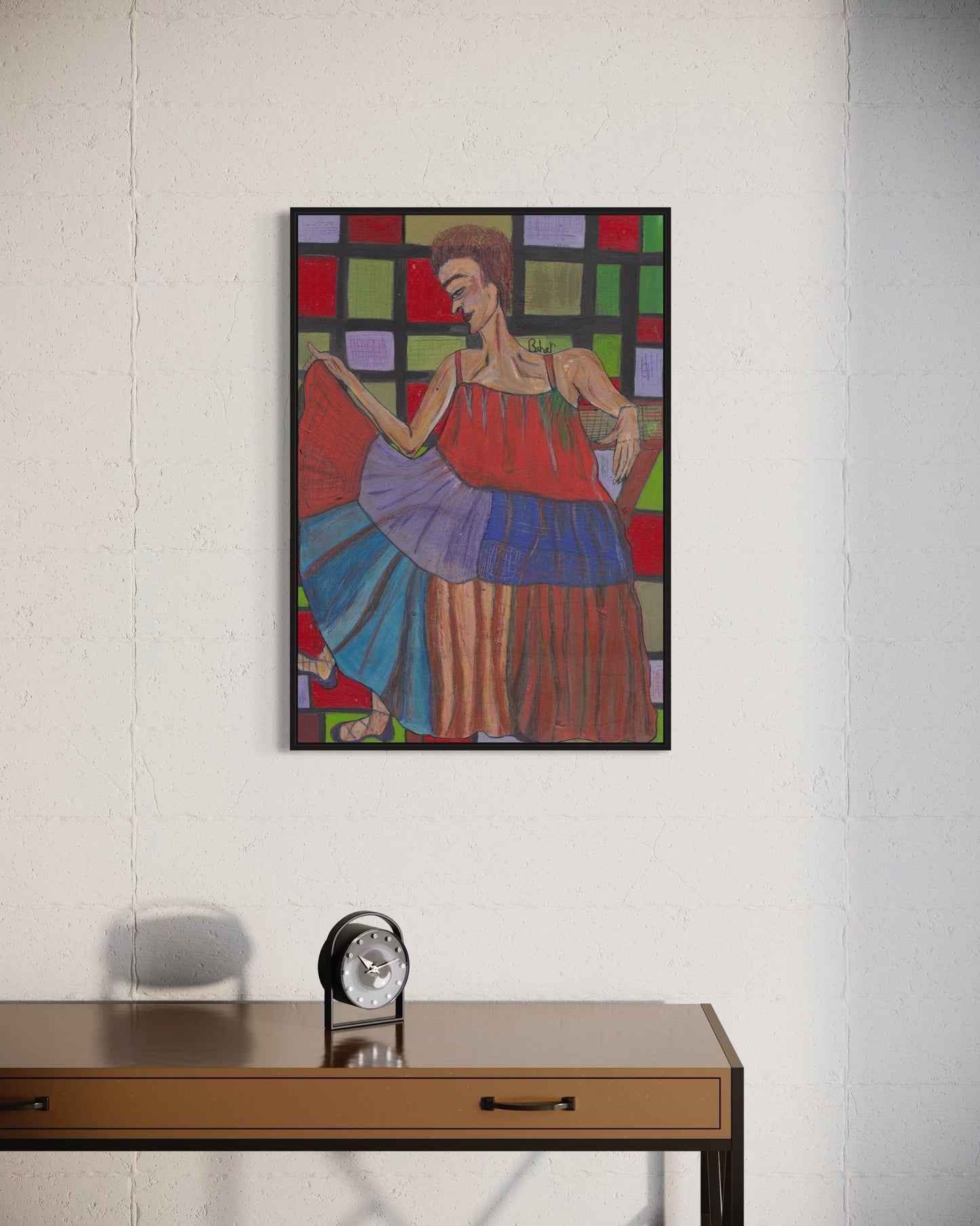Colorful abstract painting of a woman on a white wall above a wooden desk with a clock.