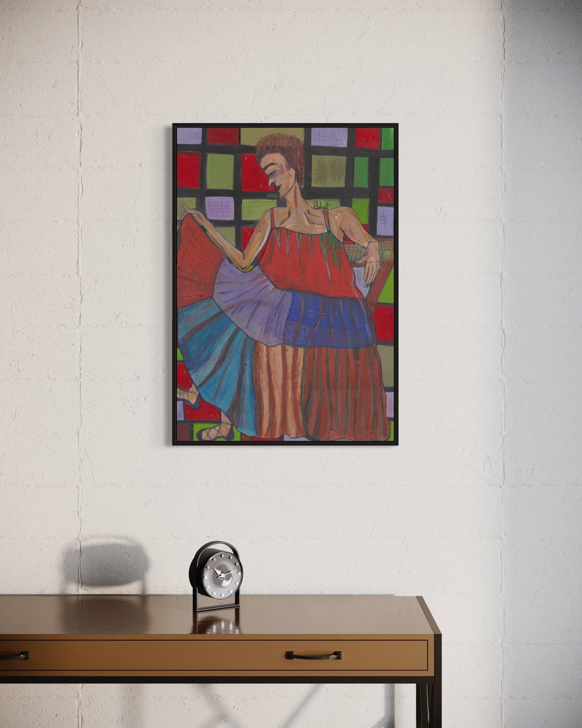 Colorful abstract painting of a woman on a white wall above a wooden desk with a clock.