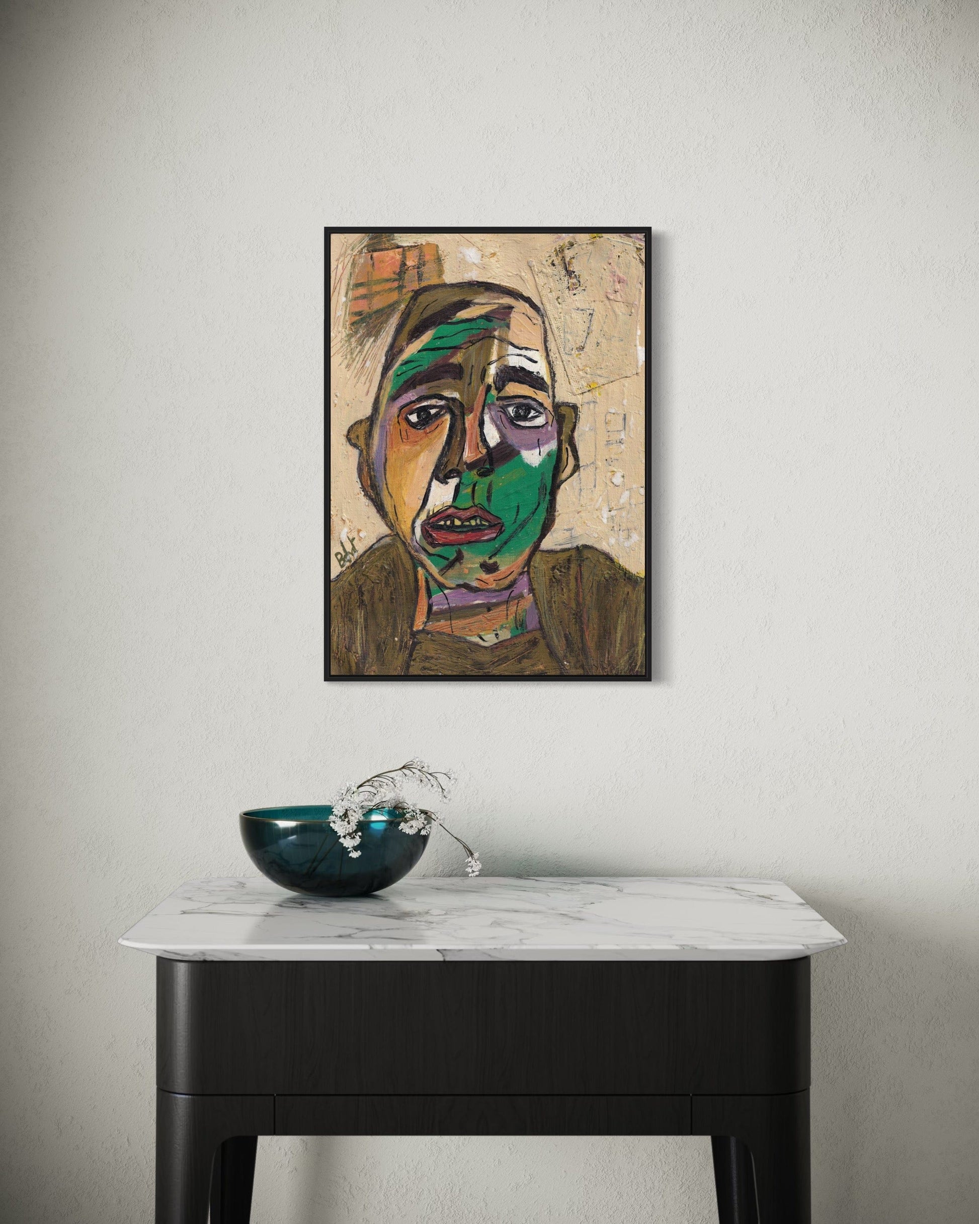 Framed abstract artwork on a wall above a marble table with a decorative bowl.