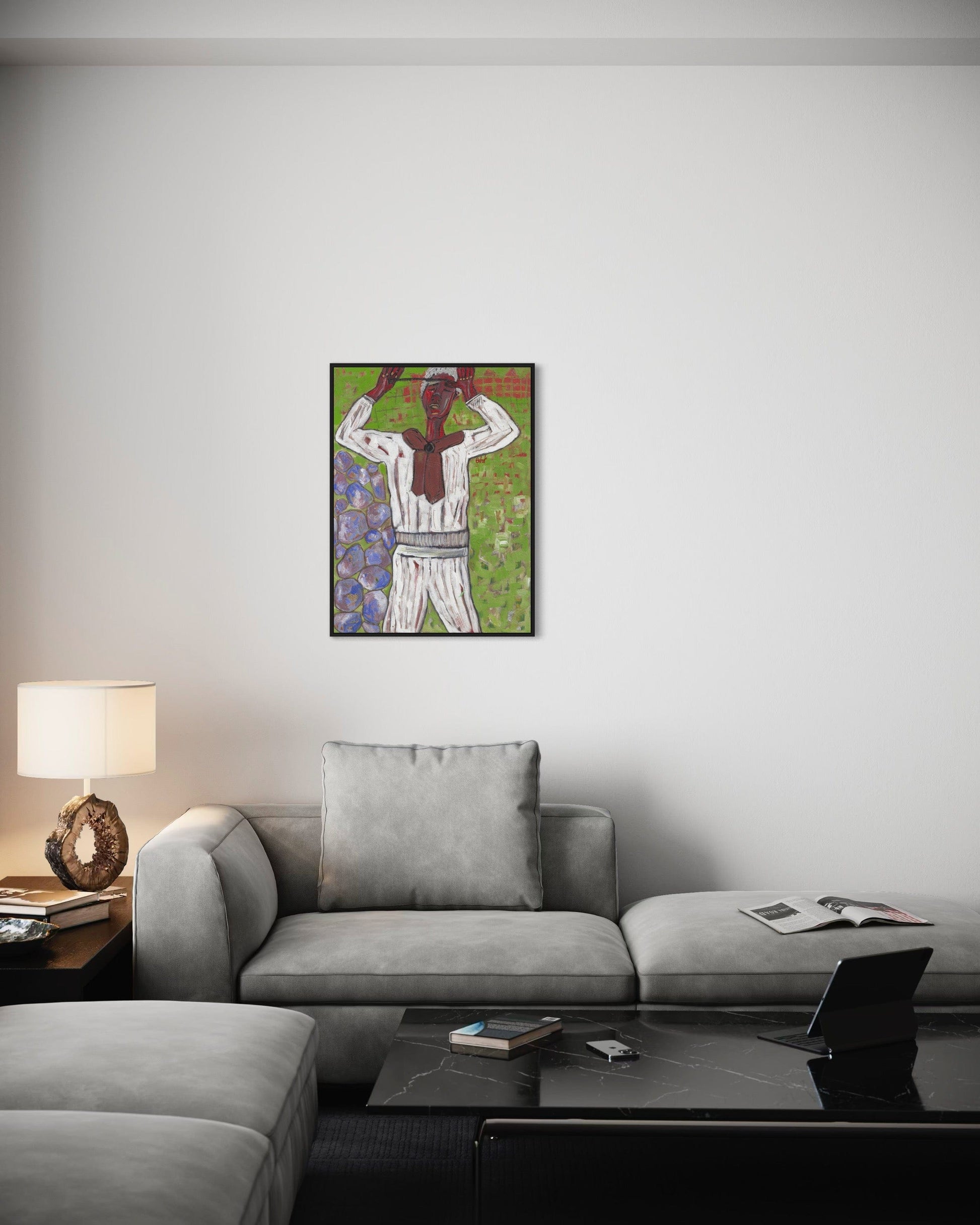 Living room with a gray sofa, coffee table, and lamp, featuring a colorful painting of a baseball player on the wall.