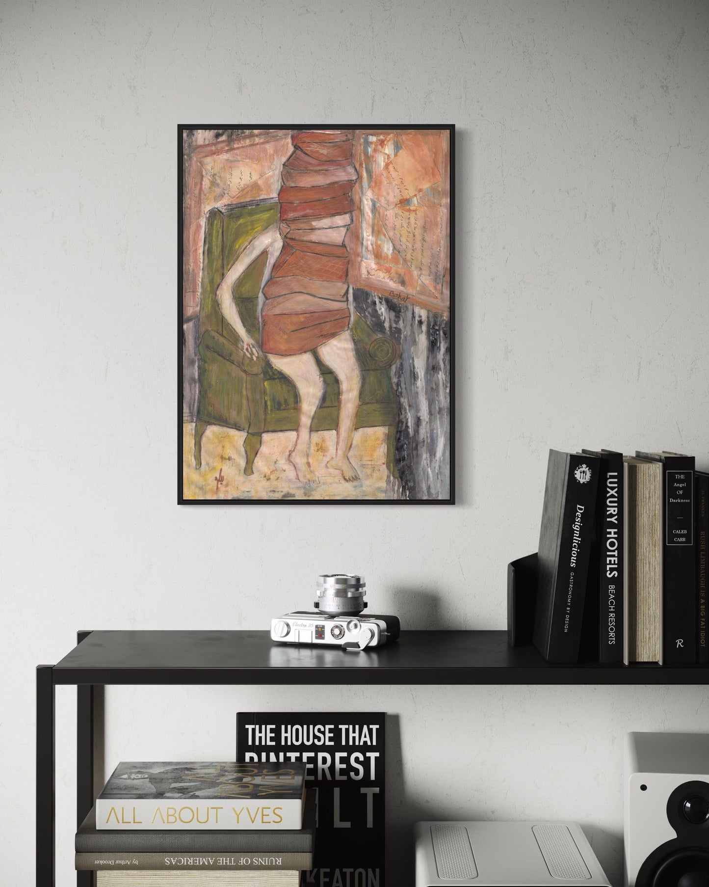 Framed artwork on a wall above a shelf with books and decor items.