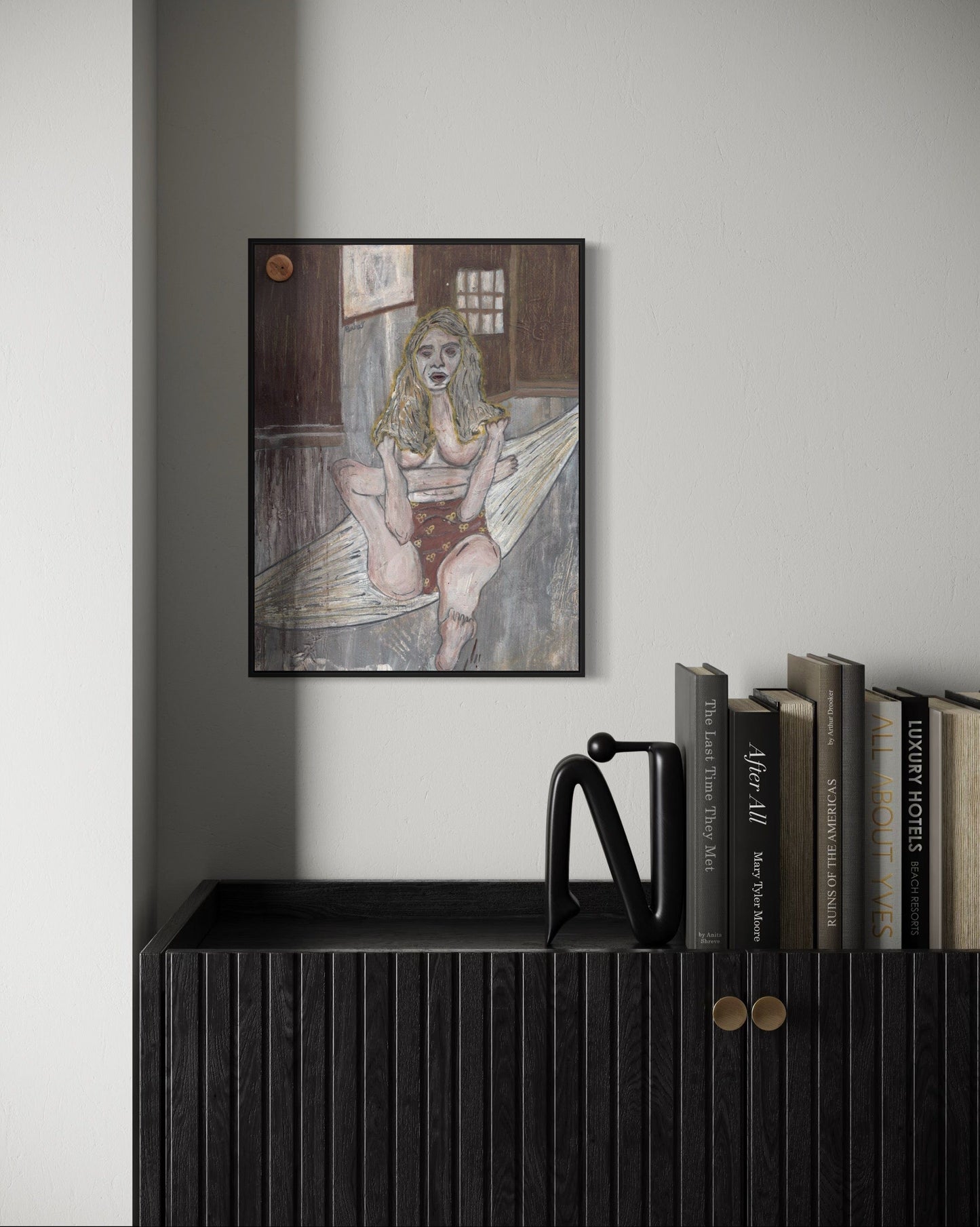 Framed artwork of a woman in a bathtub on a wall above a shelf with books.