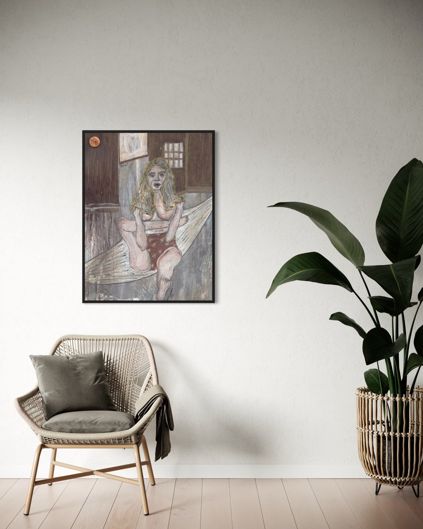 Framed artwork on a wall above a wicker chair with a plant next to it.