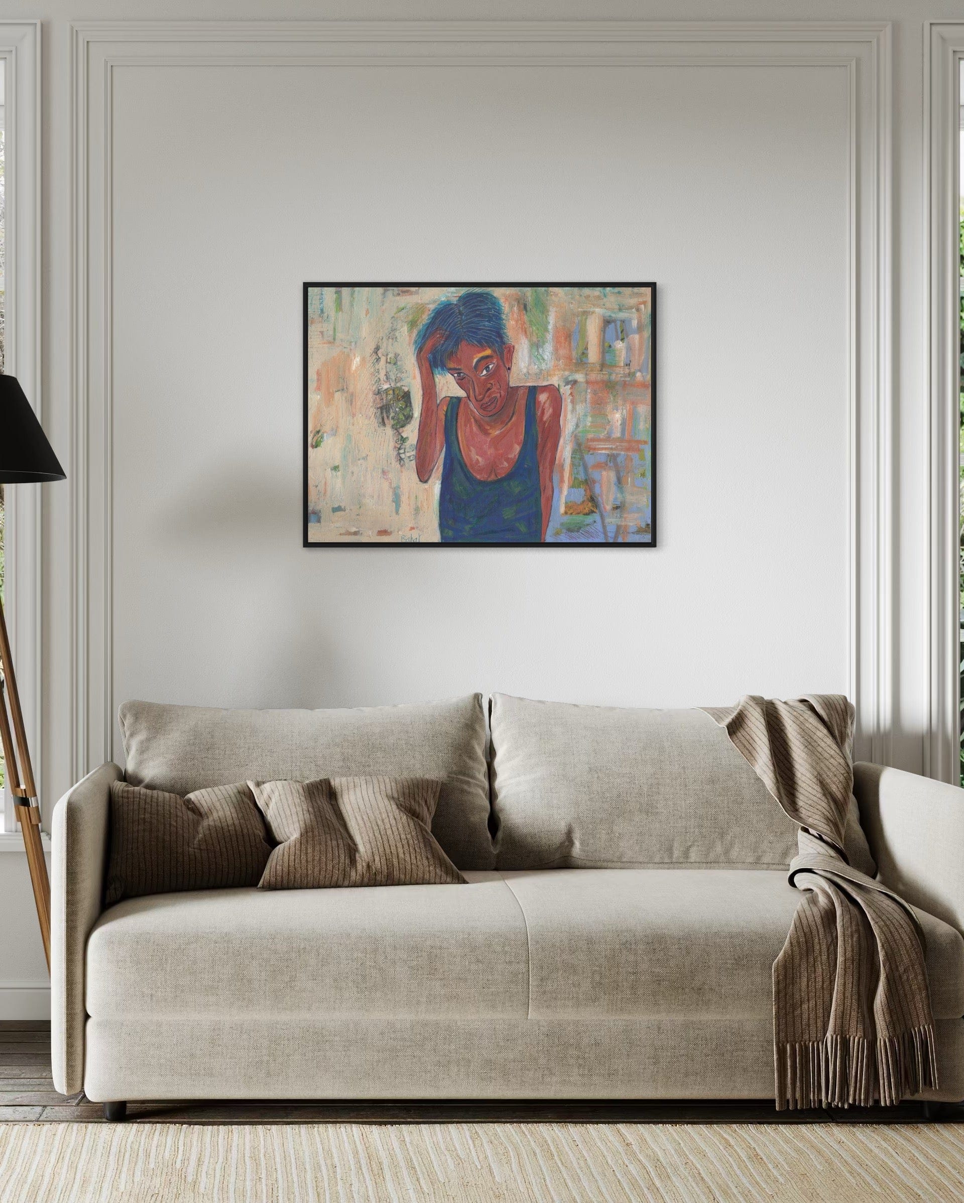 Beige sofa with decorative pillows and a blanket in a room with a colorful painting on the wall.
