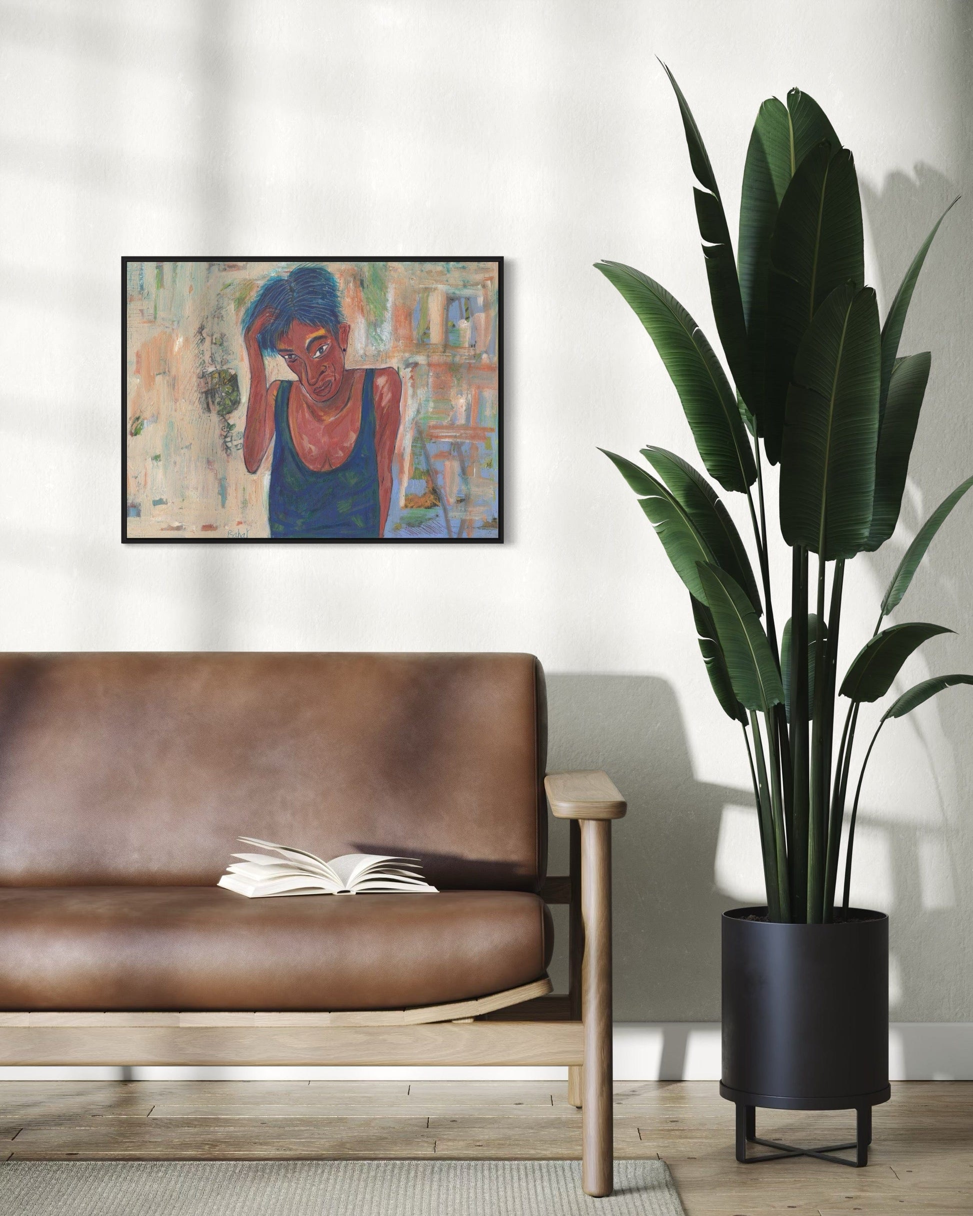 Living room with a brown leather sofa, open book, and tall plant near a framed painting.
