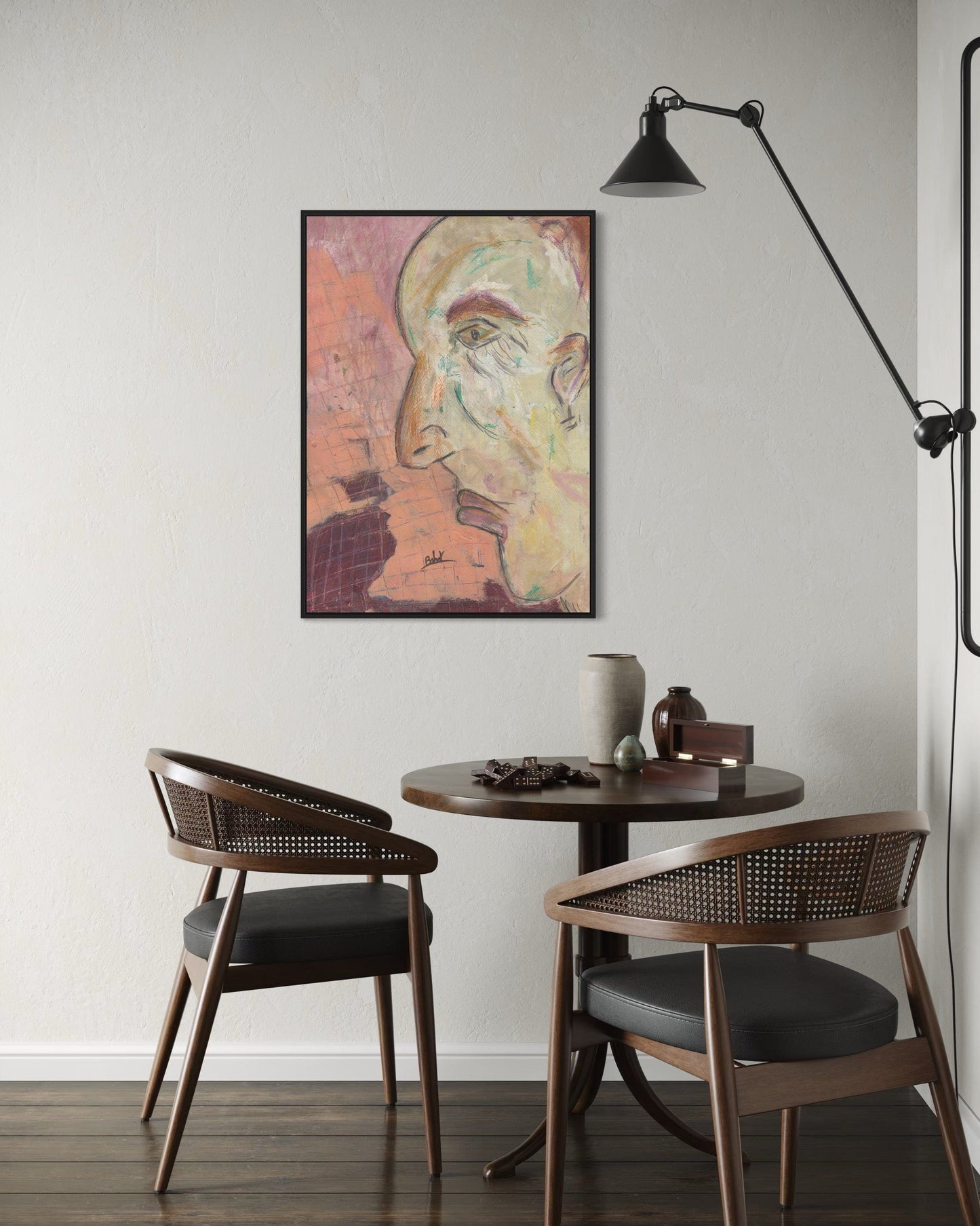 Small dining area with round table and two chairs, featuring a wall art piece of a stylized face.