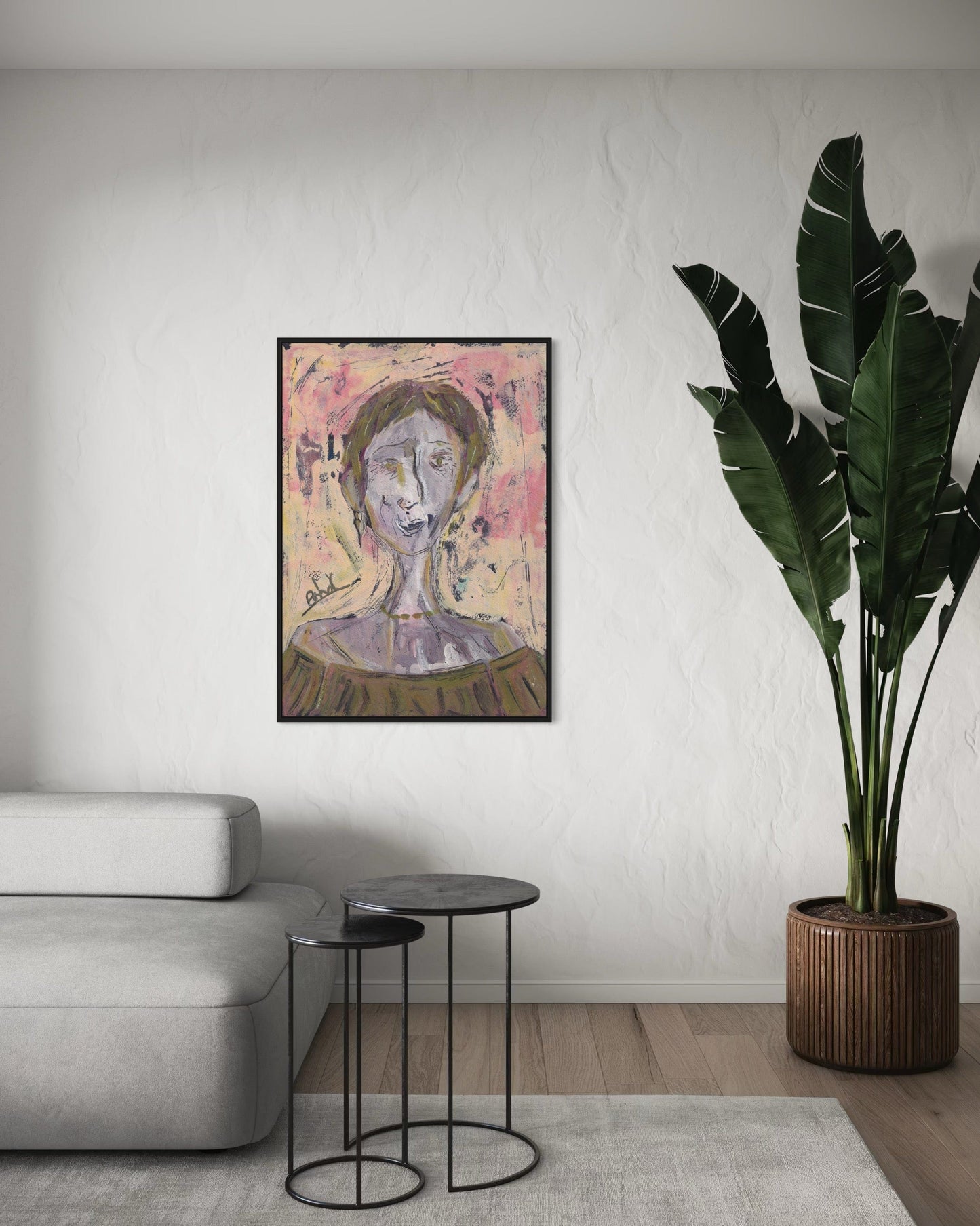 Framed artwork on a wall in a living room with a sofa and plant.