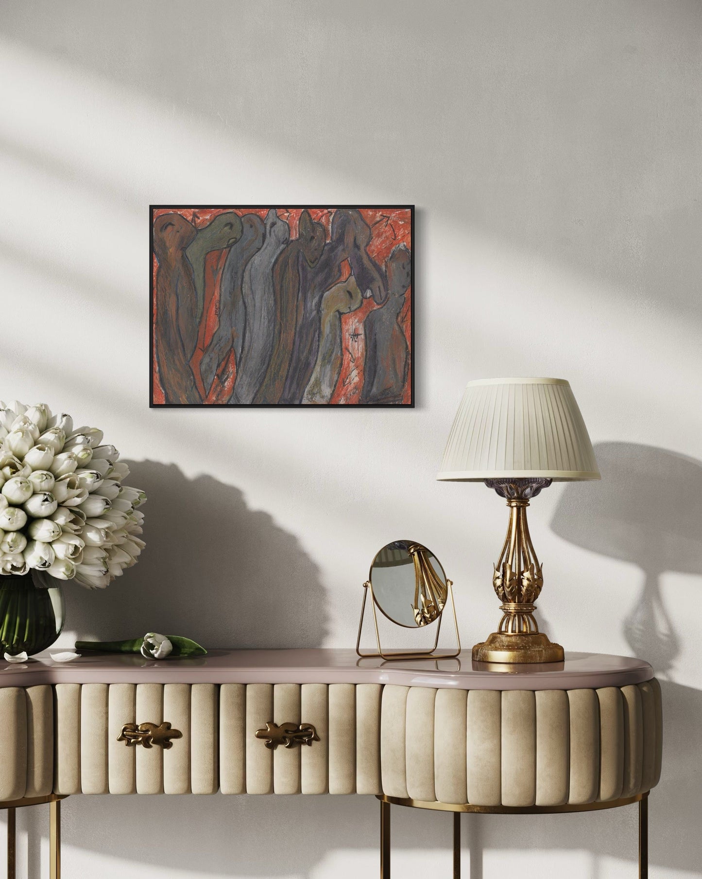 Decorative console table with a lamp, mirror, and flowers against a wall with a framed abstract painting.