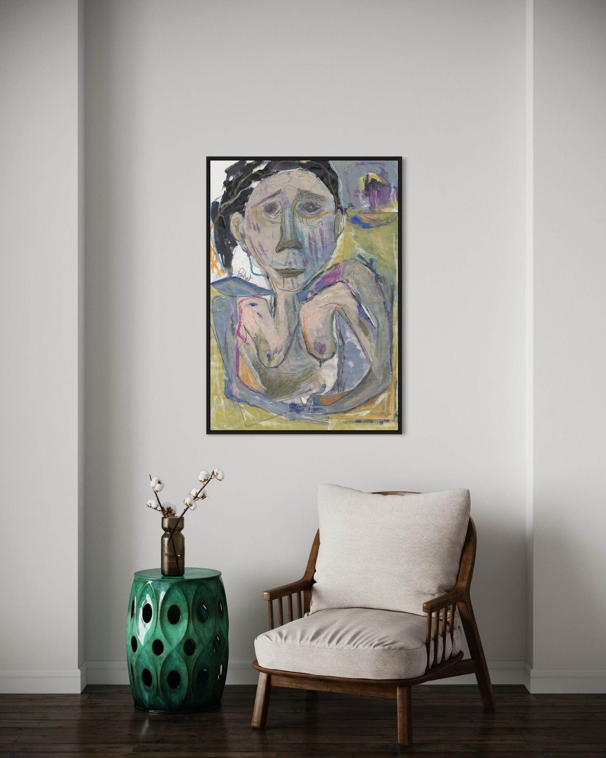Framed abstract painting on a wall above a chair and green side table.