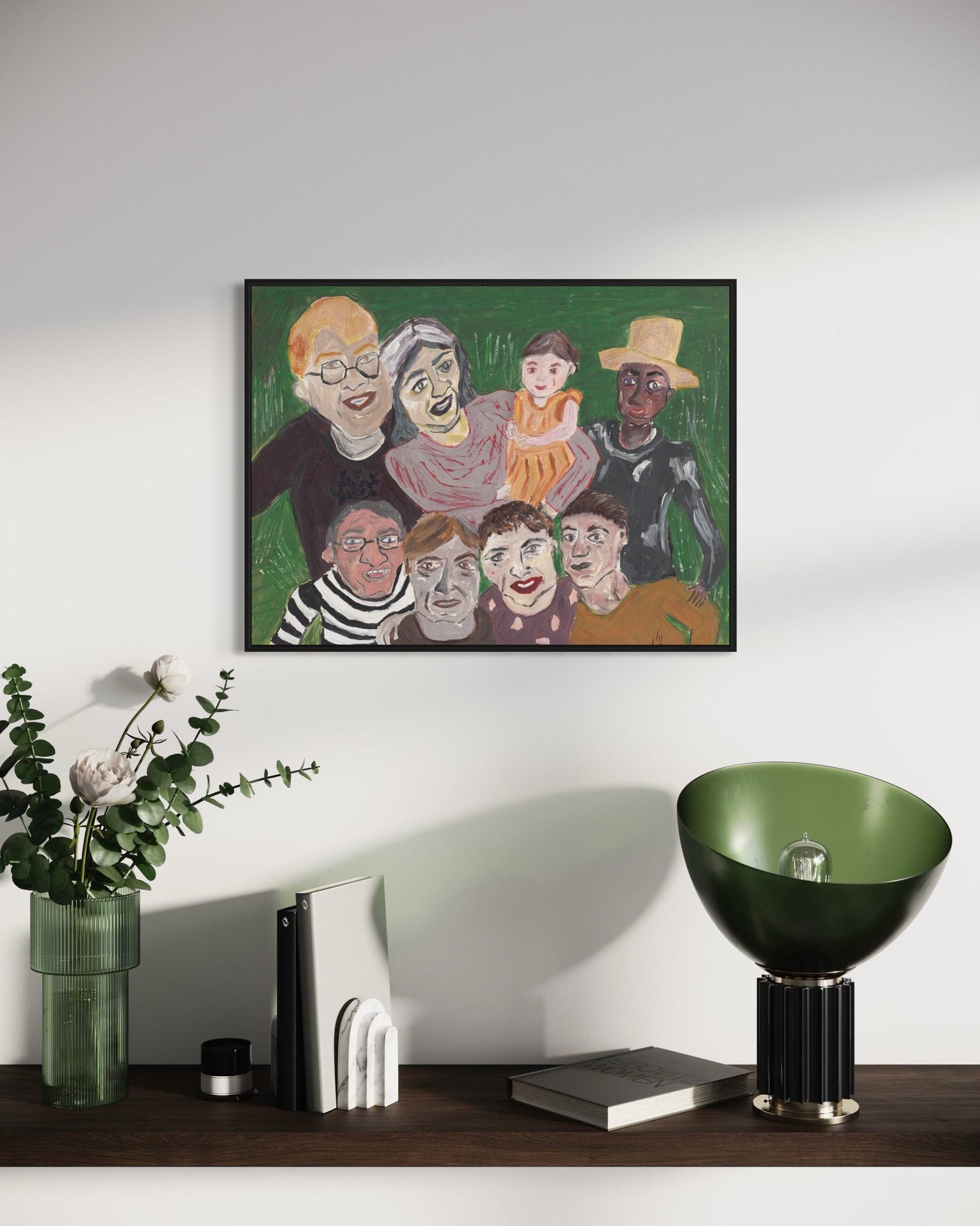 Framed artwork of a family portrait on a wall with decorative items below.