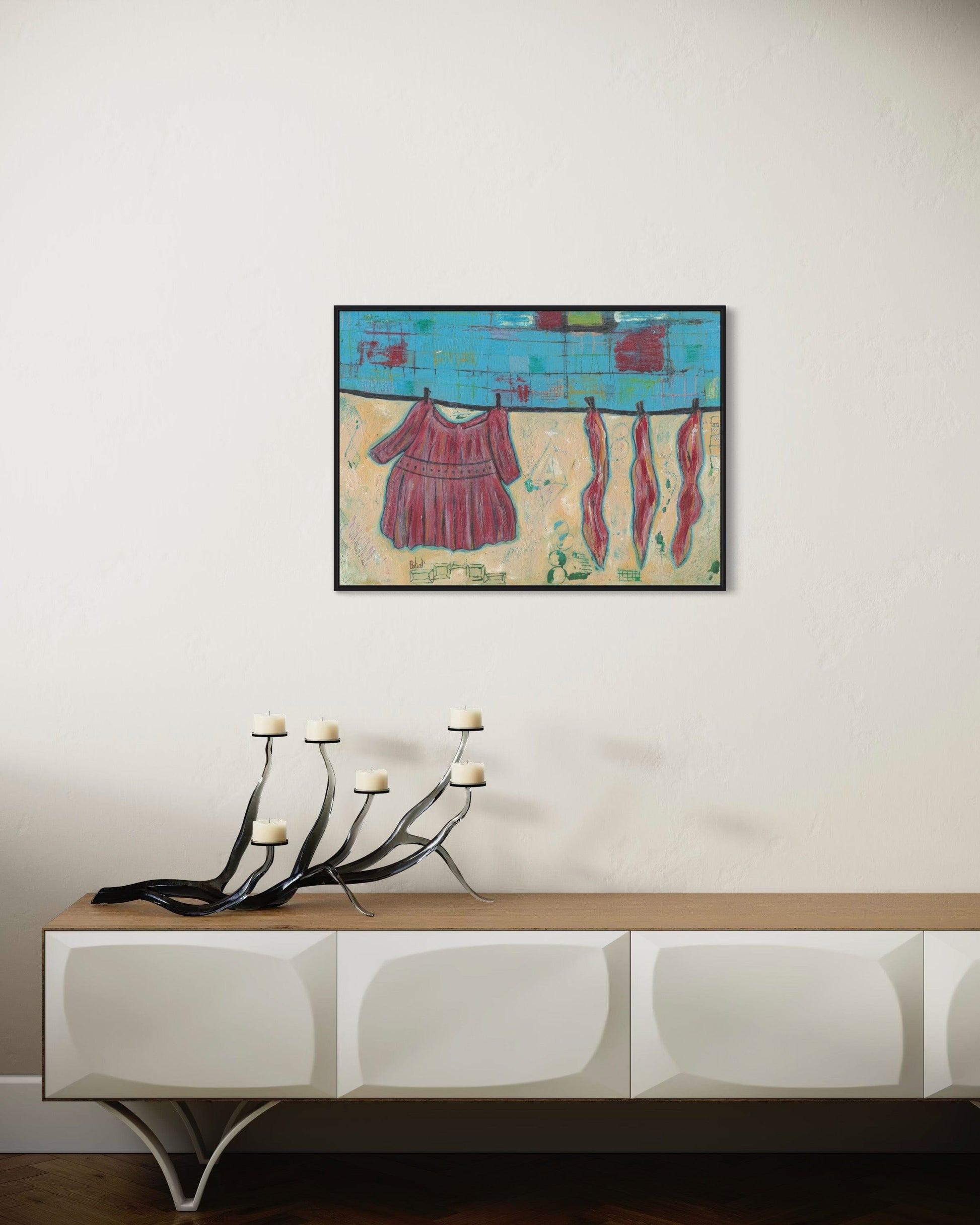 Framed abstract artwork on a wall above a console table with decorative candles.