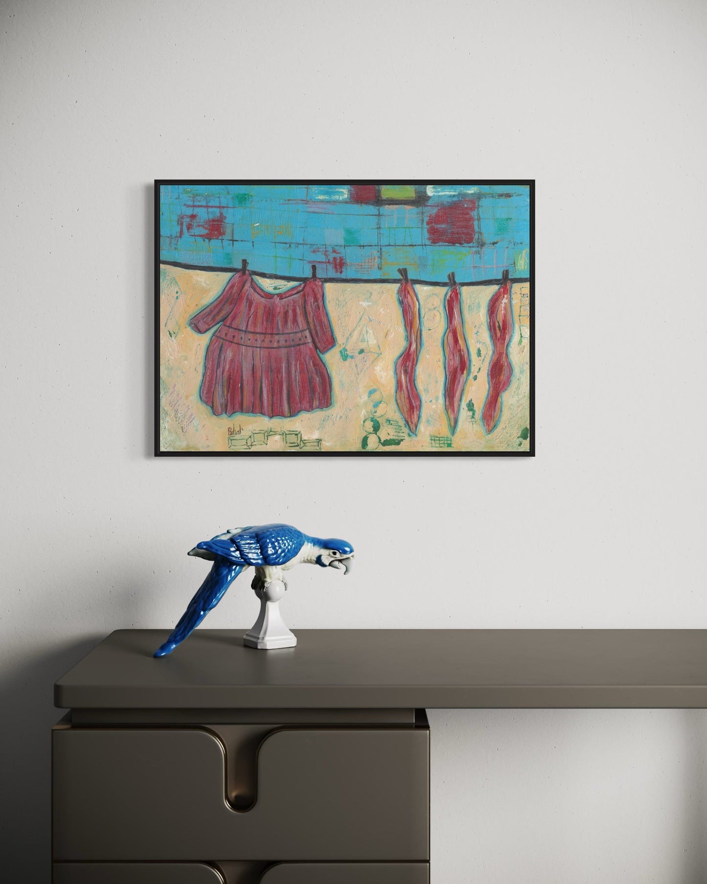 Framed abstract artwork on a wall above a desk with a decorative object.