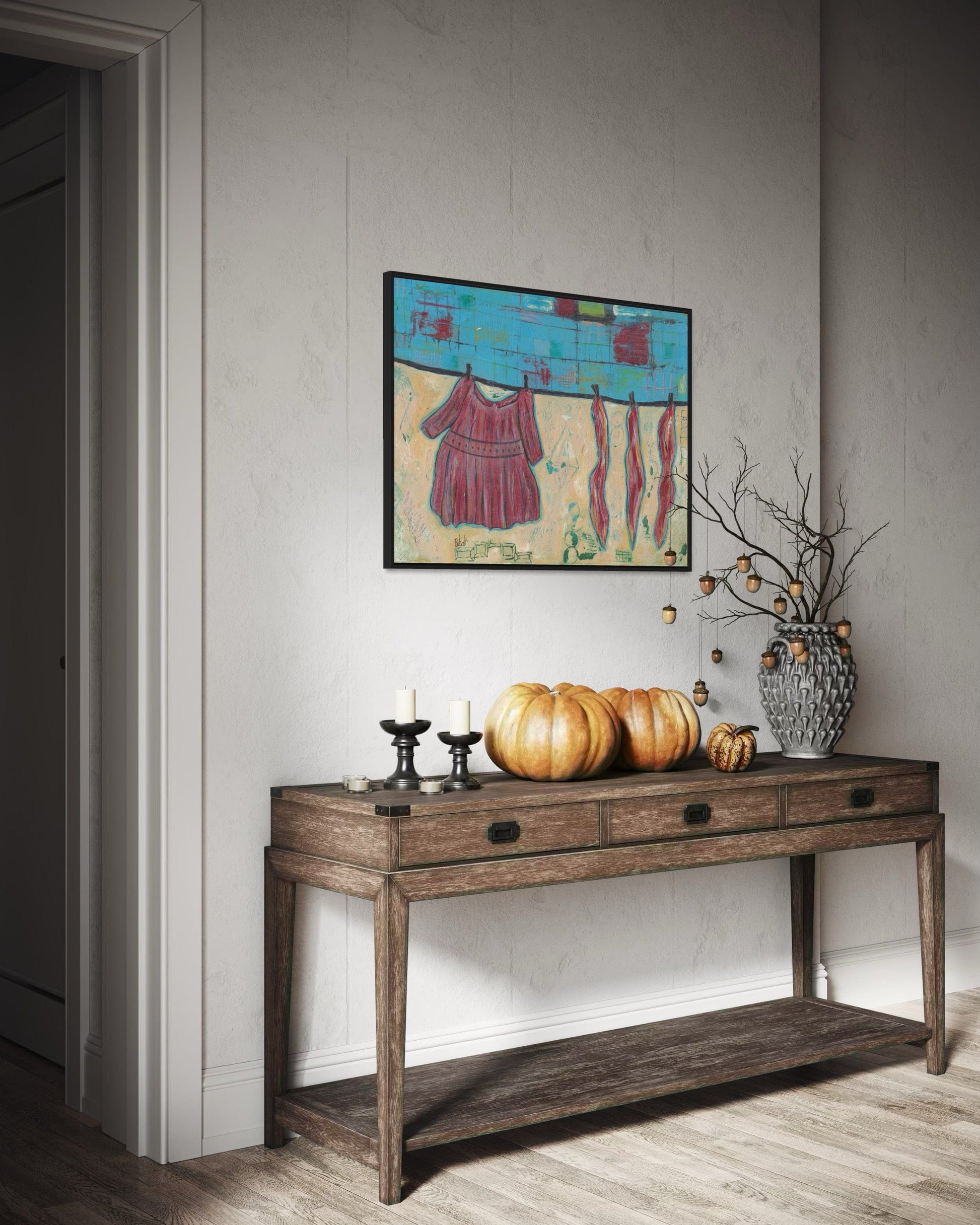 Wooden console table with decorative items against a wall with a framed abstract painting.