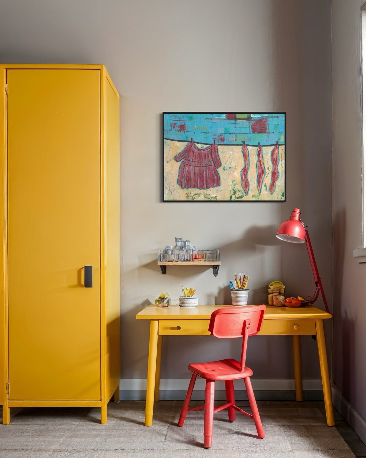Yellow cabinet, red chair, and desk with a colorful painting on the wall in a room.
