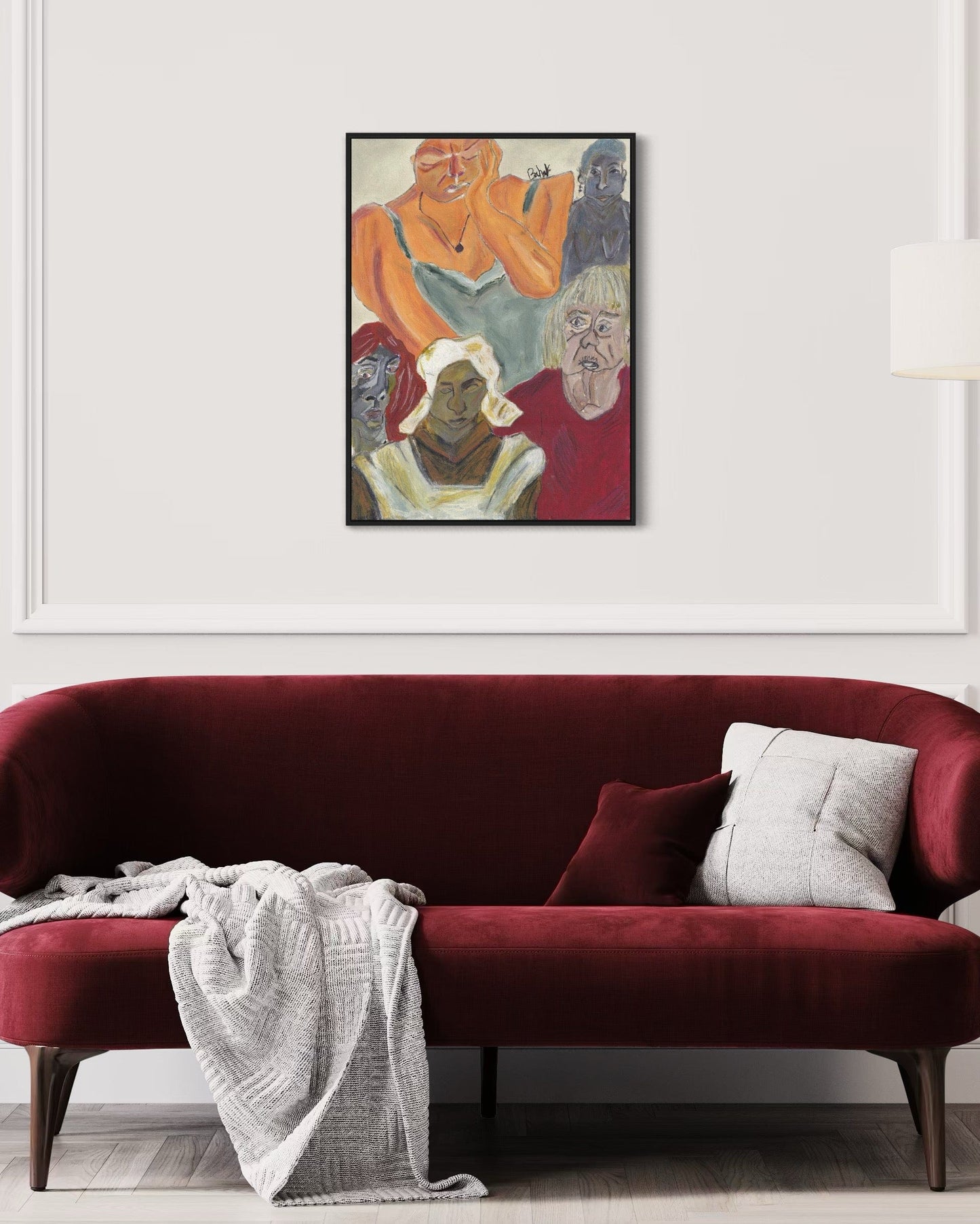 Red sofa with a white blanket and gray pillow, framed artwork above on a white wall.