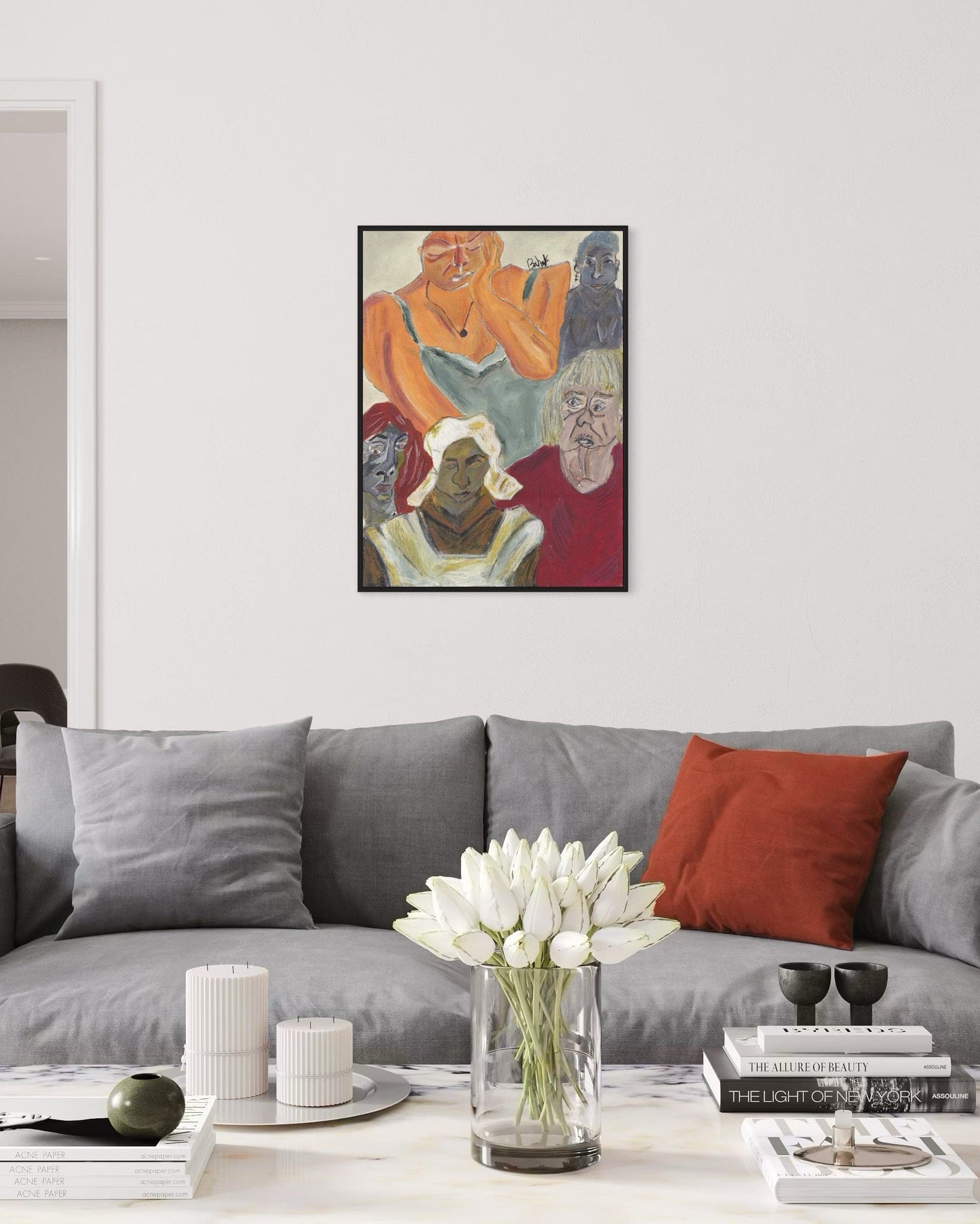 Living room with a gray sofa, red pillow, and a framed artwork on the wall.