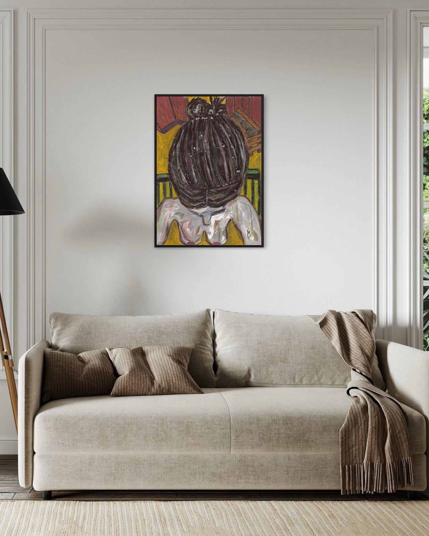 Beige sofa with decorative pillows and a blanket in a room with a colorful abstract painting on the wall.