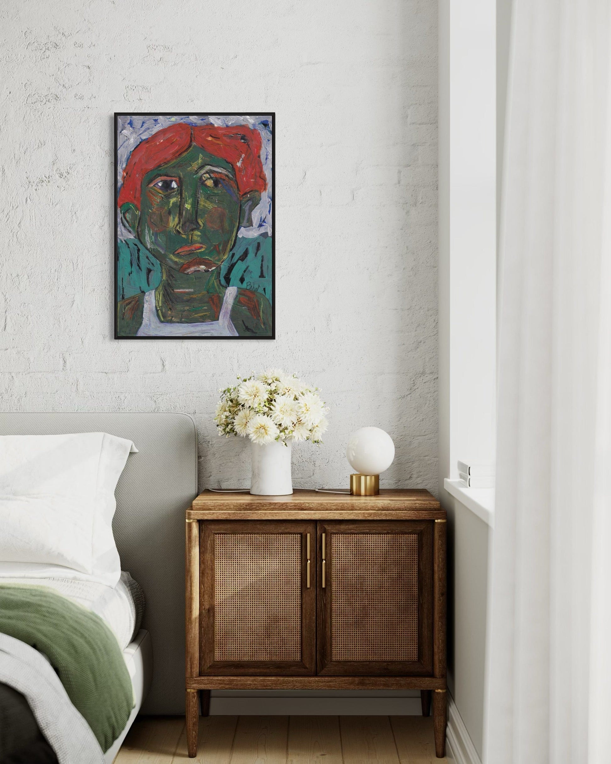 Artistic portrait on a wall above a wooden cabinet with decorative items in a bedroom.