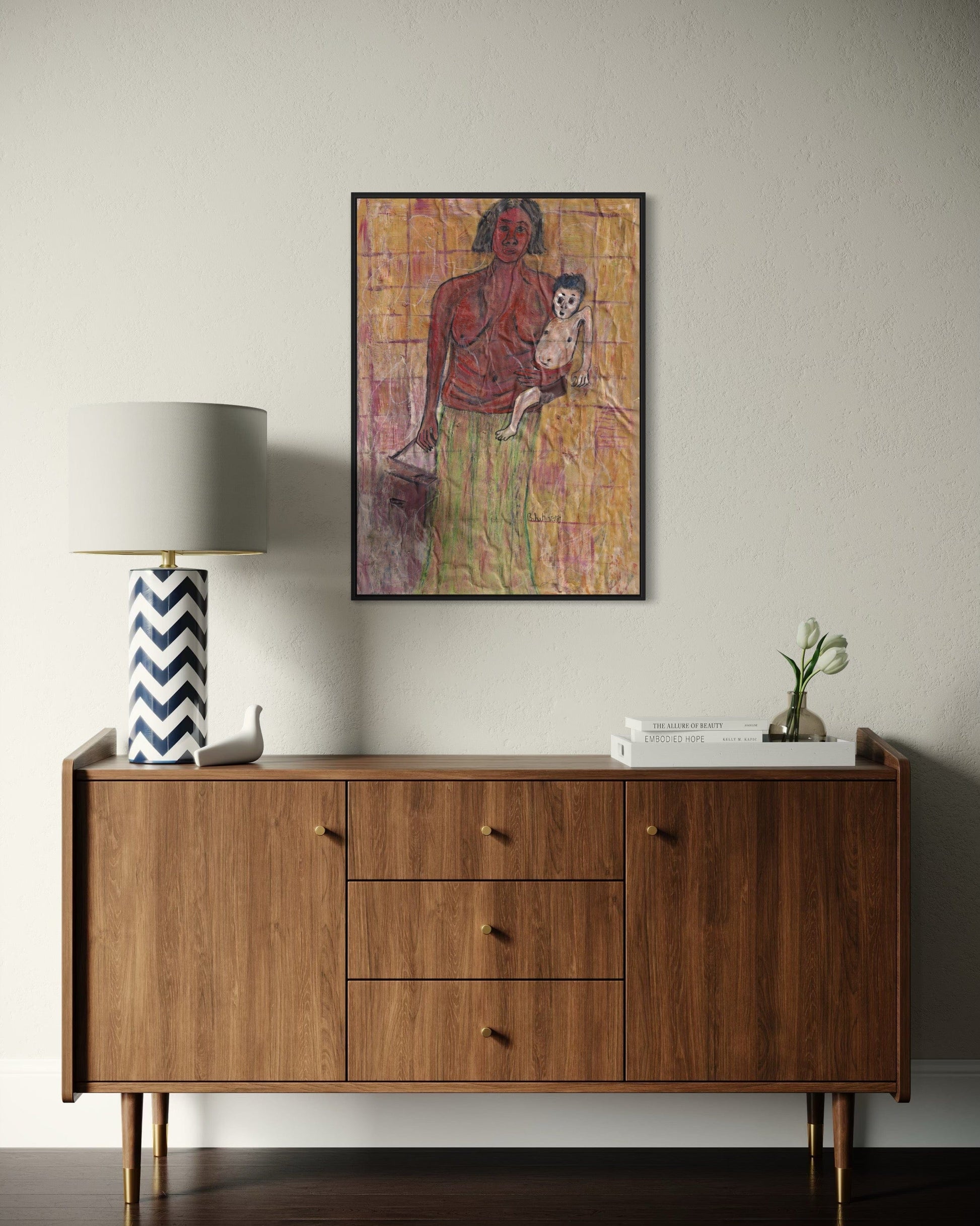 Wooden sideboard with a lamp and decorative items against a plain wall with a framed artwork.